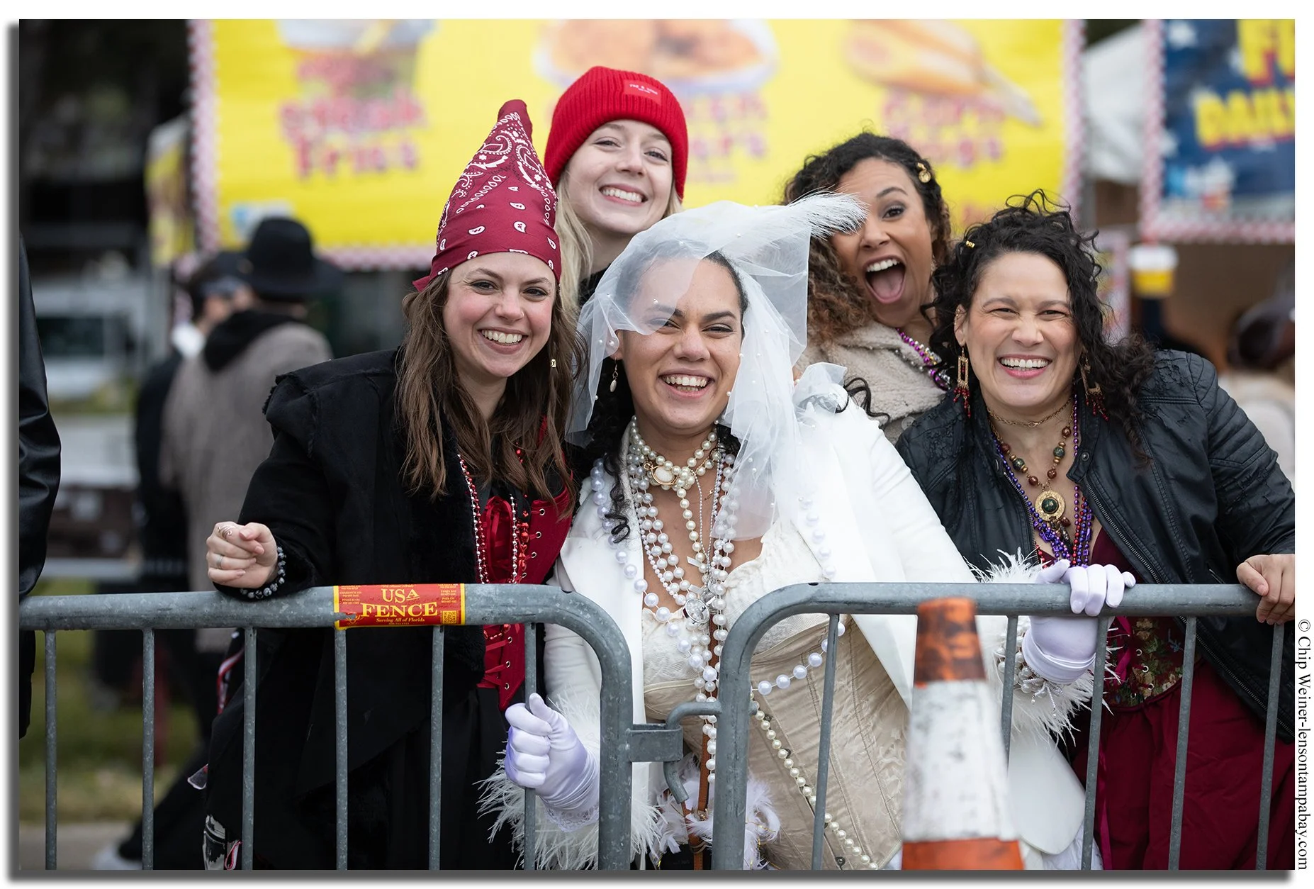 Bachelorette party in pirate costumes celebrating Gasparilla Pirate Fest in Tampa, surrounded by crowds, beads, and parade floats.