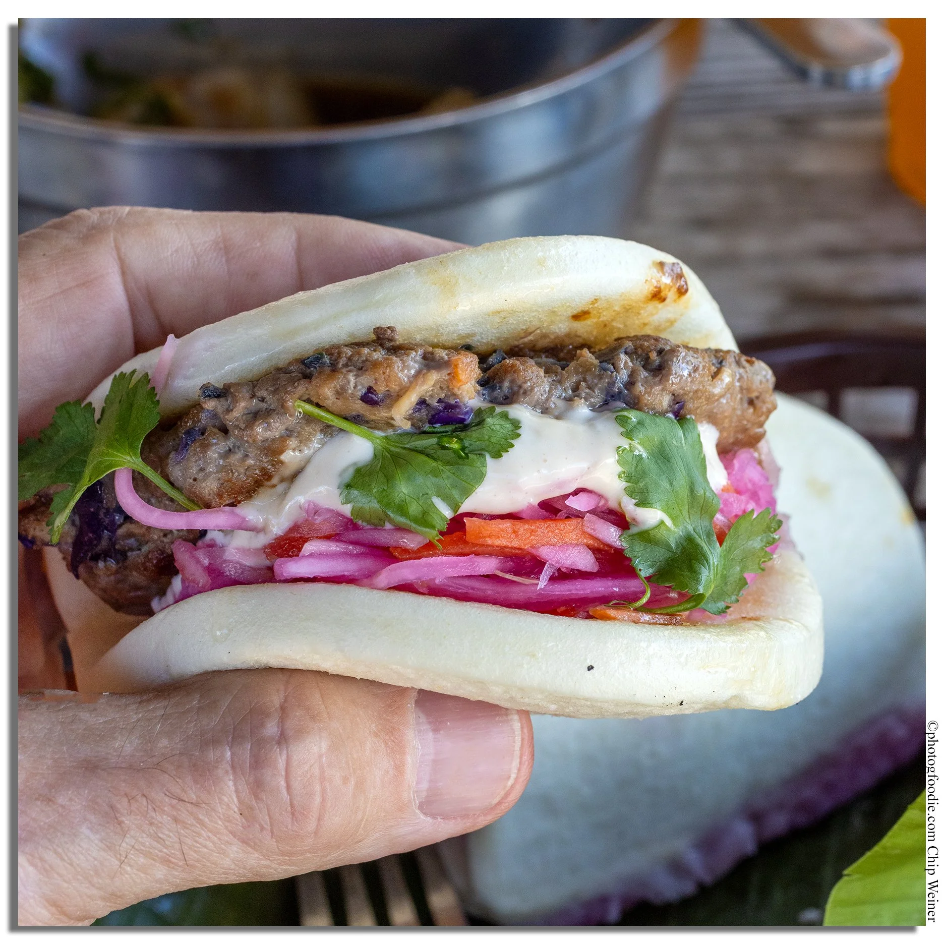 Lumpia smash burger bao at Lucky Tigre in Tampa with creamy sauce, pickled onions, and cilantro
