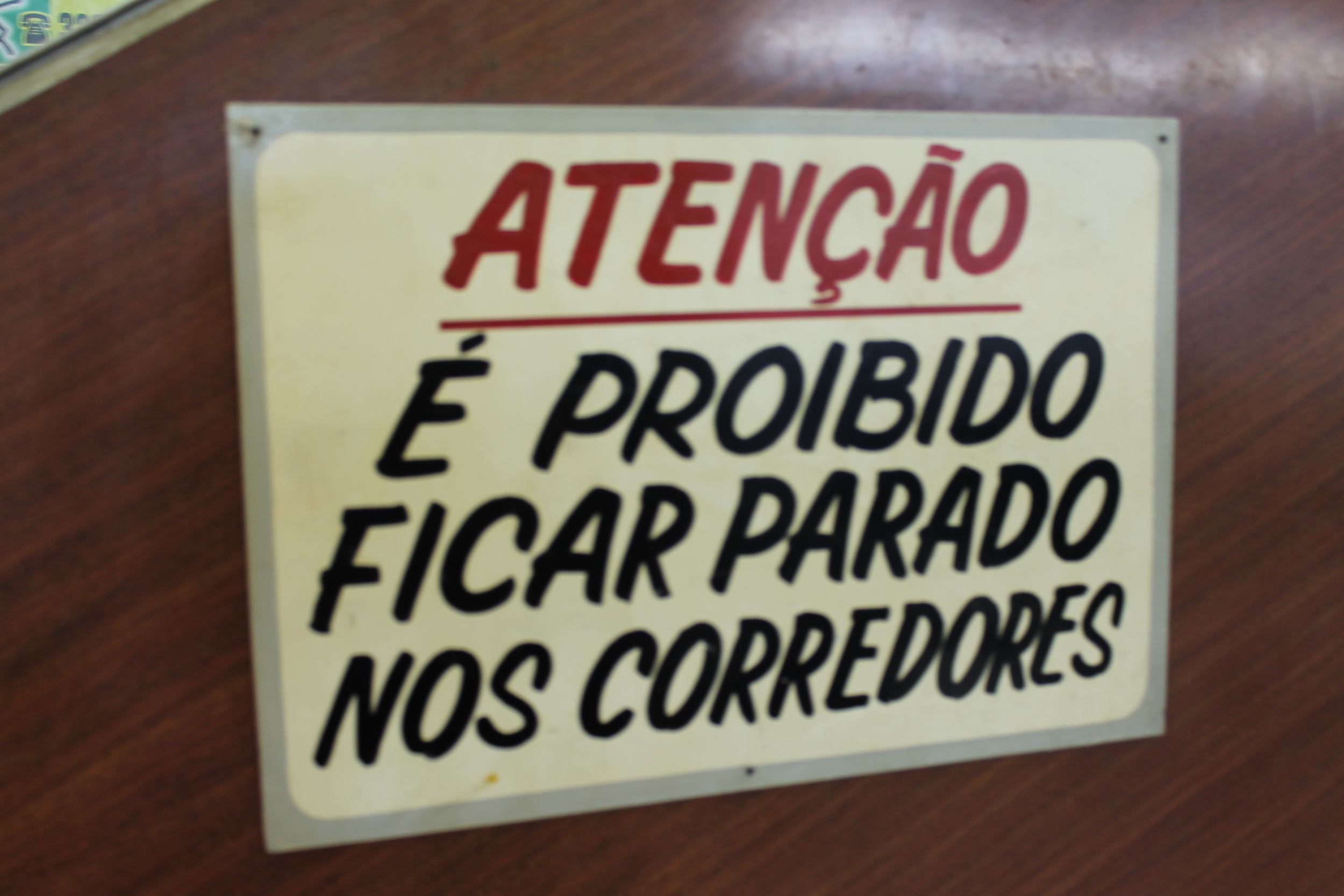 Essa placa fica na Galeria do Presidente (conhecida como Galeria do Reggae) em São Paulo. O lugar que tem lojas e restaurantes, aberto como espaço público proíbe as pessoas de ficarem paradas no corredor. Como é que é possível olhar as vitrines, então? E como um espaço público pode ser proibido a circulação? 