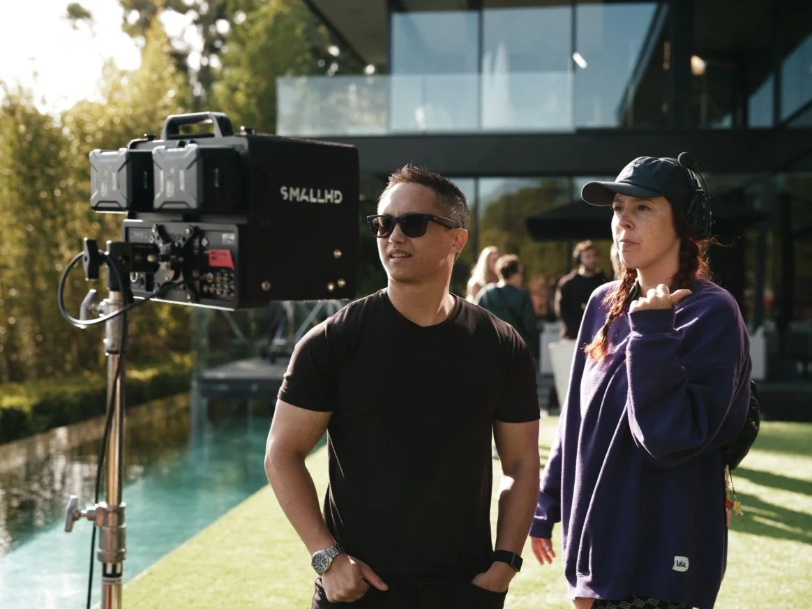 Two crew members review a SmallHD field monitor on set outdoors, checking color and exposure during production.