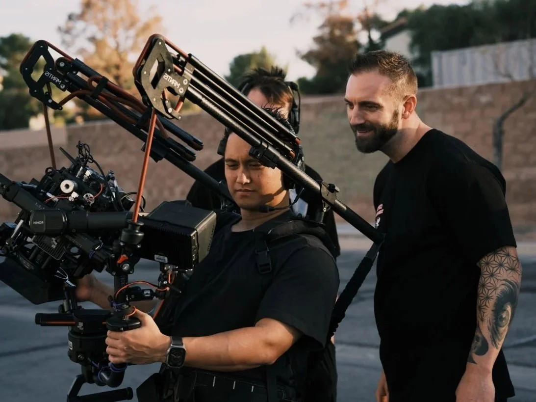 A client reviews a field monitor over the camera operator's shoulder.