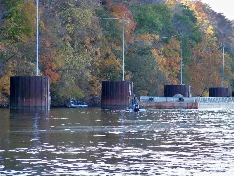 Anchored barges, fish the up current side of the barge. The barge will displace water at the upstream end. Presumably the bass will hold under the barge just behind the current break waiting for food to come to them. When your lure hits the current break they jump on it.