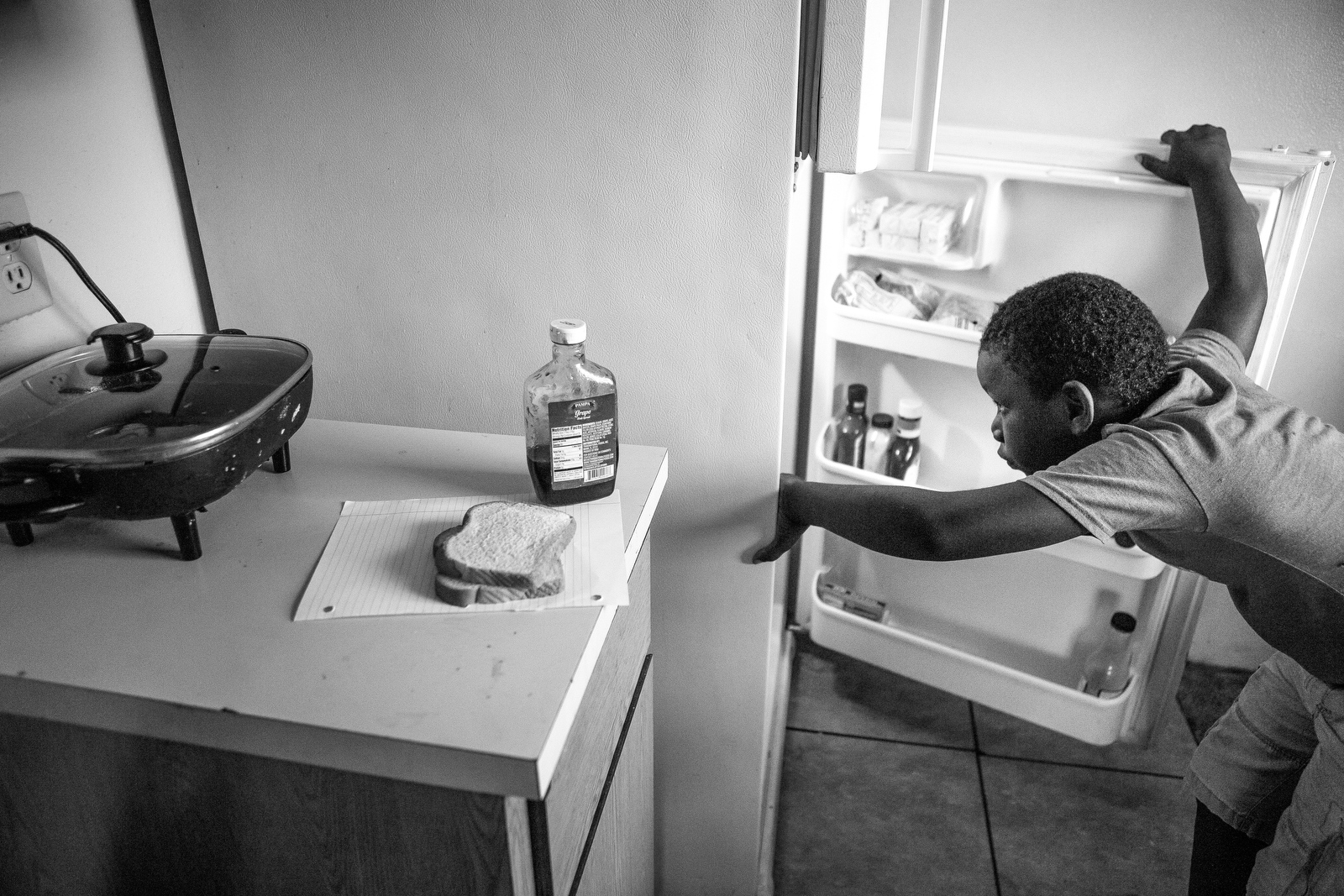  Donald Gibson, 8, checks the refrigerator before making a peanut butter and jelly sandwich at the home where he lives with his grandparents. Their previous home burned down and now Donald's grandmother Imogene only has one electric skillet to cook m