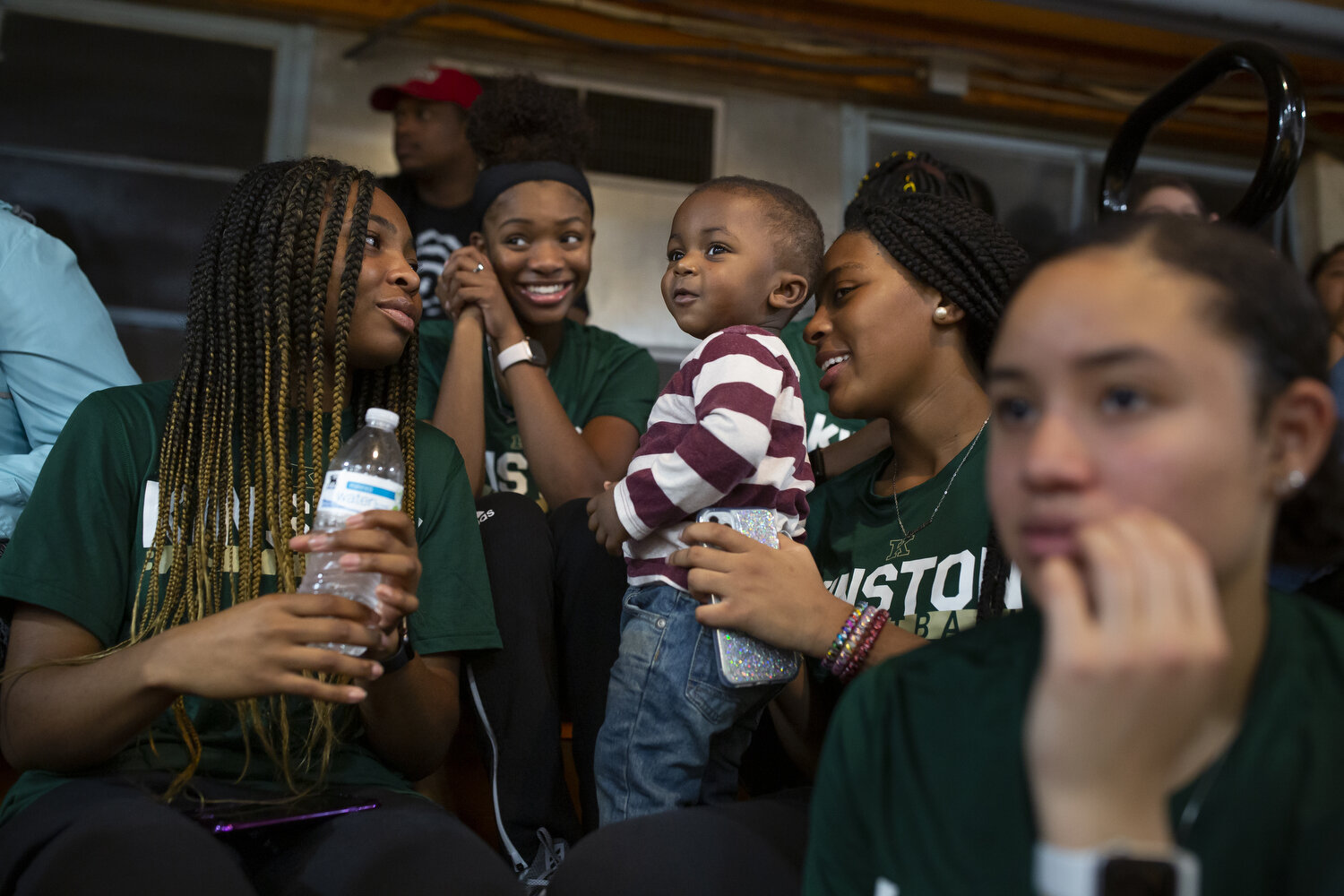  (Left to right) After their game, Kinston players Kahlia Hargett, Lesley Sutton, Quiaira Powell, and Alena Rivers sit in the stands with a friend's son to watch the boy's team play South Lenoir High School. 