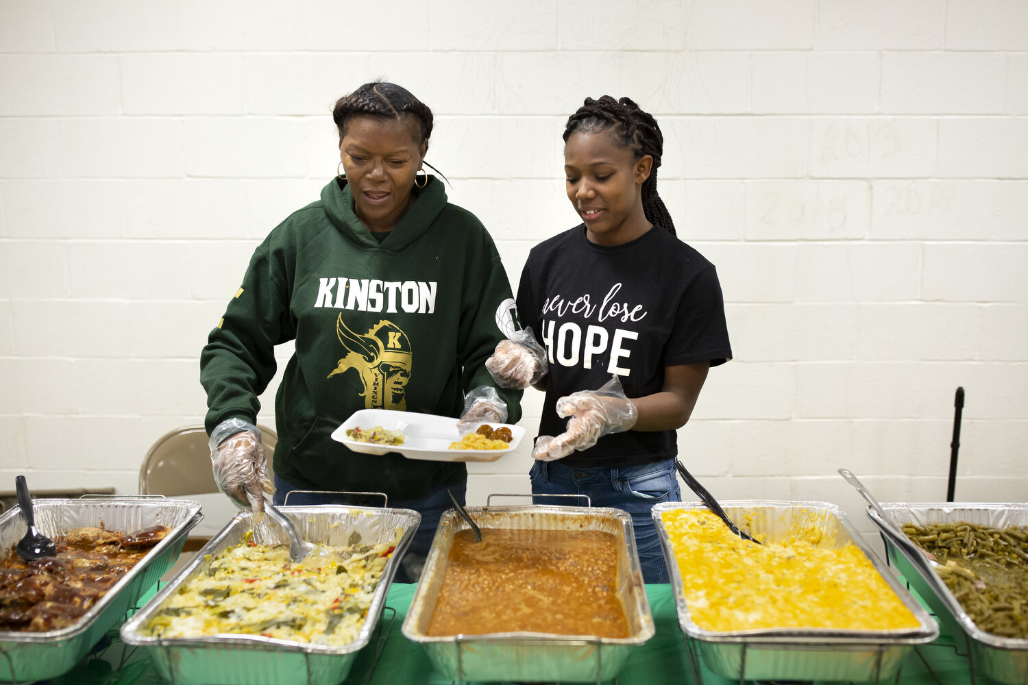  Lori Carmon, left, whose daughter Michyla Dove plays on the team, and team assistant KJay Johnson, right, serve food during the jamboree games hosted by Kinston High School. Carmon woke up at one a.m. that morning to start cooking all of the food. S