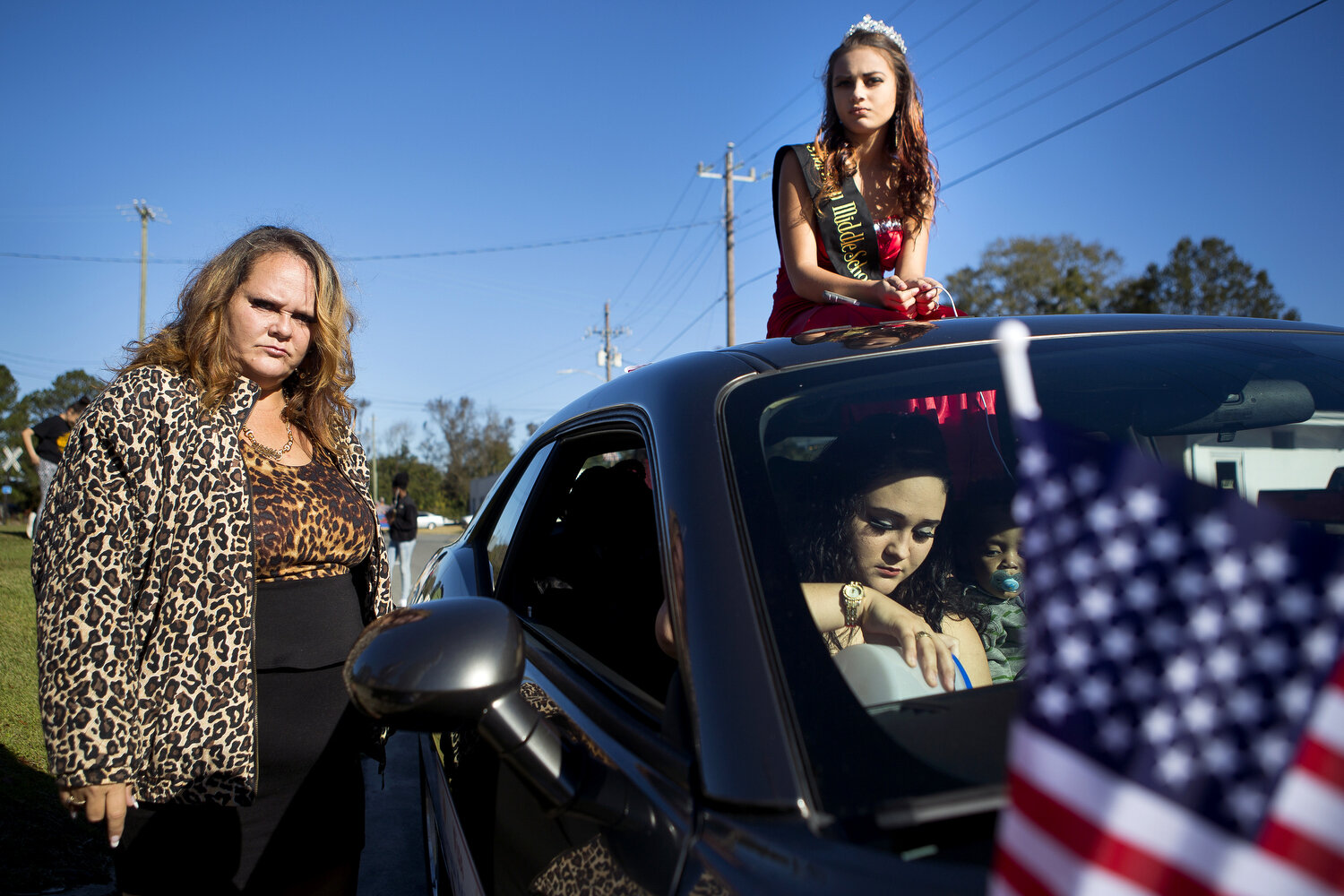  Miss Warsaw Middle School Zequoia Sanderson sits on top of a car for the 96th annual Warsaw Veterans Day parade as her mom Cathy Barden, left, and Zena Bell, in the car, prepare to ride in the parade as well. 
