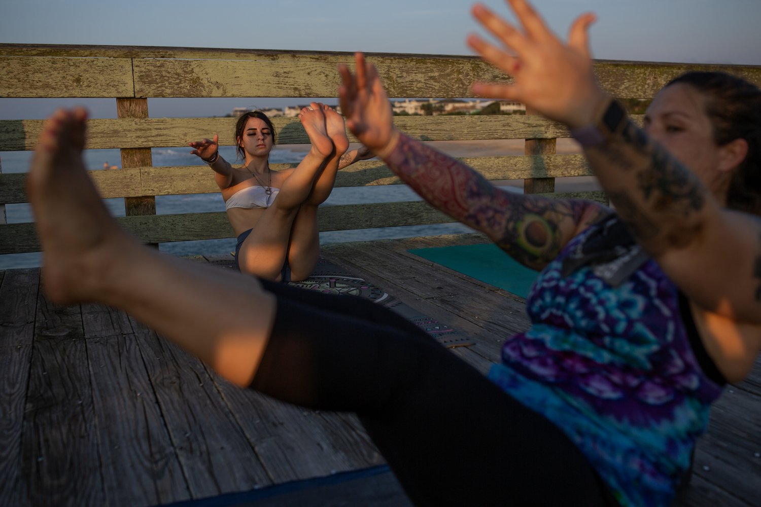  Kara Torres, left, participates in a sunrise yoga class led by Caroline Cooley, right, on the Crystal Pier at Wrightsville Beach, North Carolina. Cooley explains that doing yoga early in the morning means that you get it in “before the sun starts to