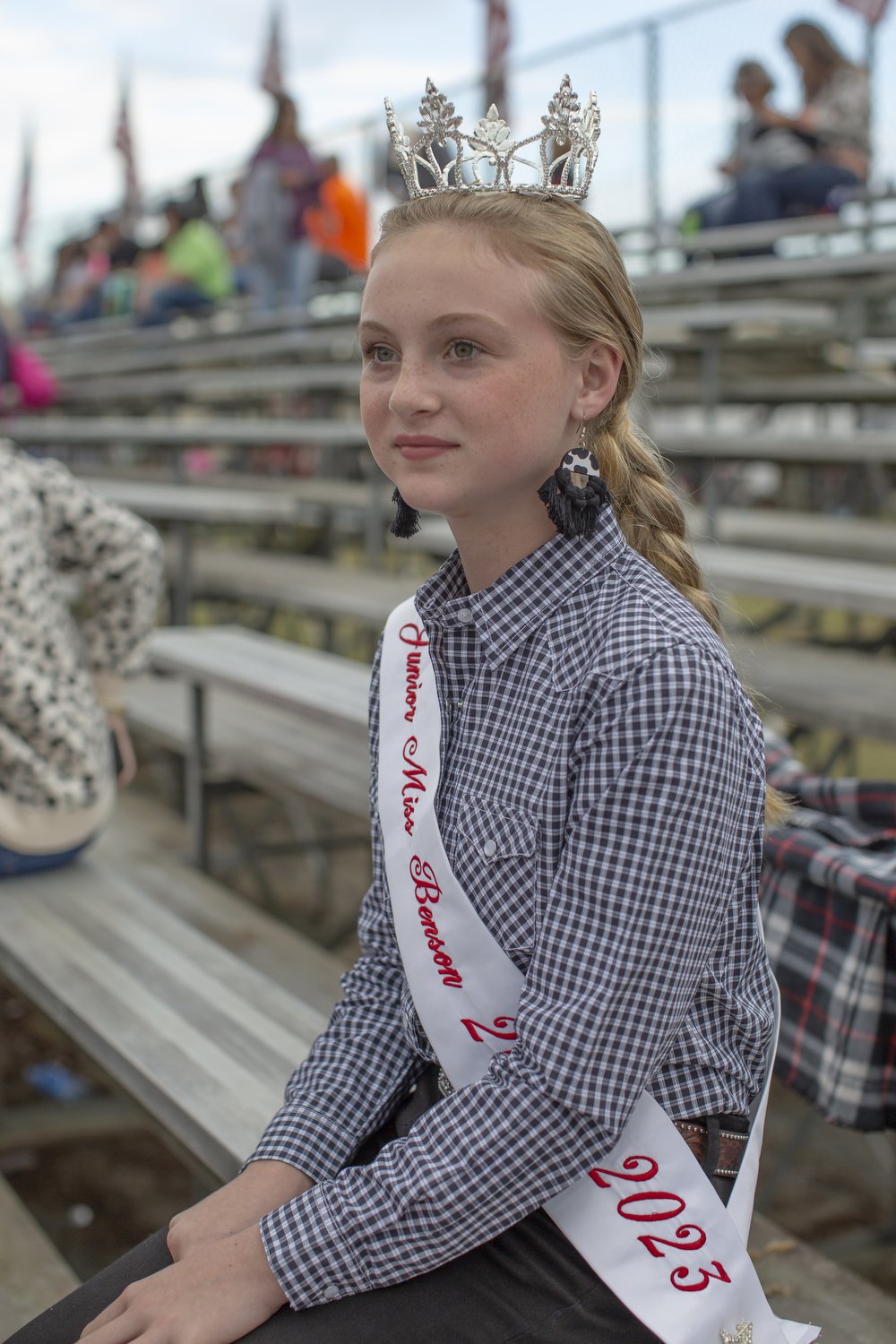  Carly Rae Johnson, Junior Miss Benson 2023, sits in the stands before the rodeo at Mule Days in Benson, North Carolina.  For Cardinal &amp; Pine 