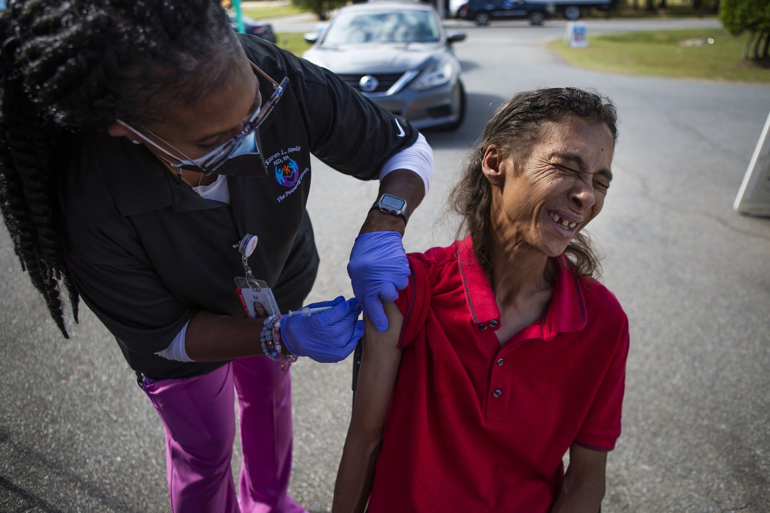  Tammy Locklear, right, winces as she receives her very first Covid vaccine from Debra McLeod, left, during an outdoor clinic hosted by Dr. Karen Smith in Raeford, North Carolina.  For The Assembly 