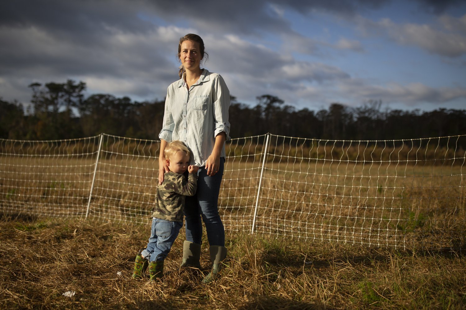  Rachel Shenk, right, and her son Mason Shenk, 3, left, stand in the open-air turkey enclosure on their farm in Newport, North Carolina. Rachel explains that one of her primary motivations in starting a farm was “so that we could do it as a family.” 