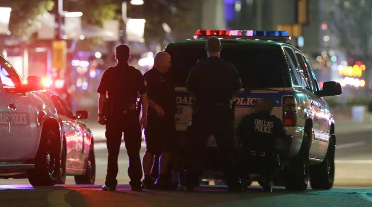 Police take cover behind a vehicle outside a parking garage in downtown Dallas early Friday, July 8, 2016. (AP Photo)