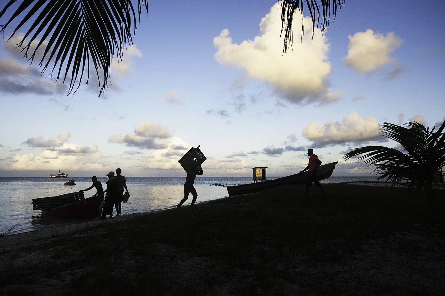 Kids who have been out at sea for over eight months on trap boats, stack wooden lobster traps at Faraway Cay to store for the brief off season. Many of these kids are only 15 and 16 years old and have brutal working conditions.