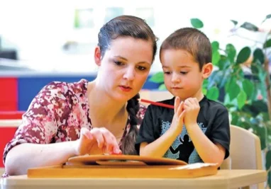STAFF PHOTO JASON IVESTER Teacher Amy Chiodo helps Byrce Larson, 4, learn numbers on a clock Wednesday at the preschool at The Jones Center. 