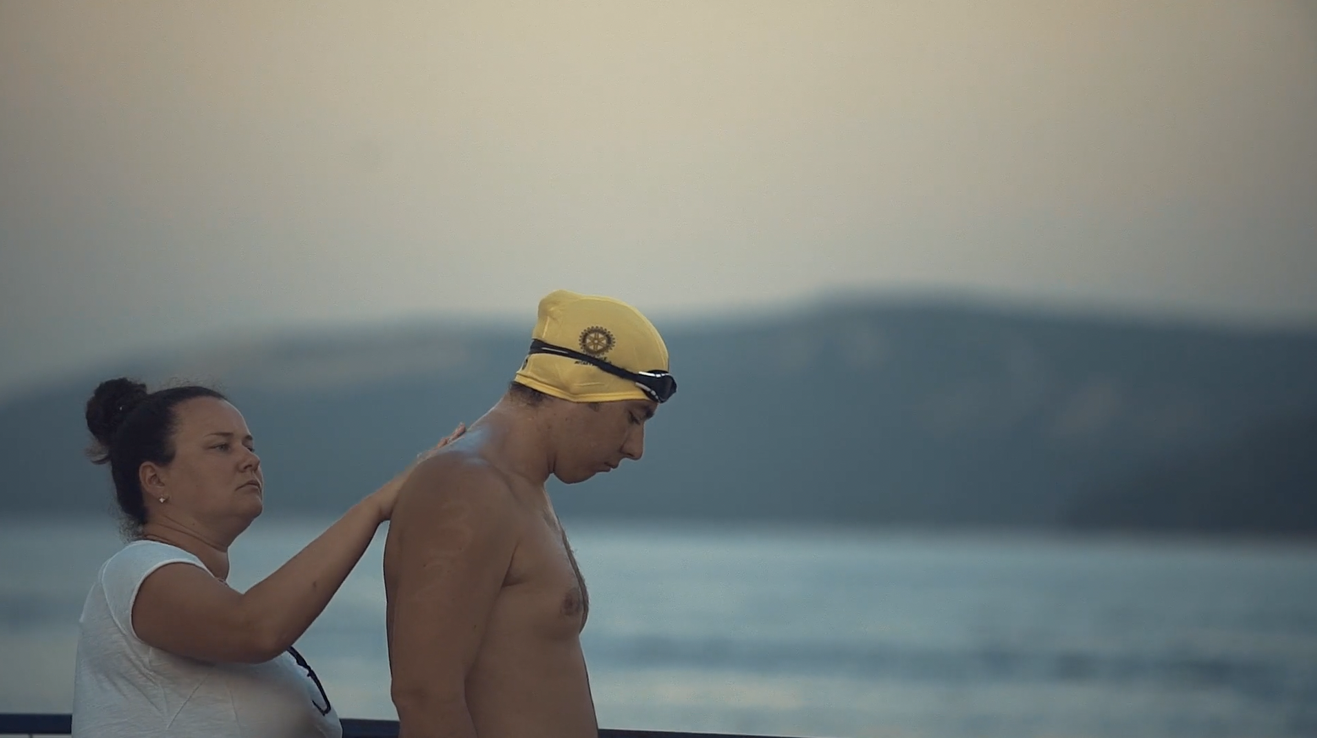 A woman helps a man prepare for a swimming race