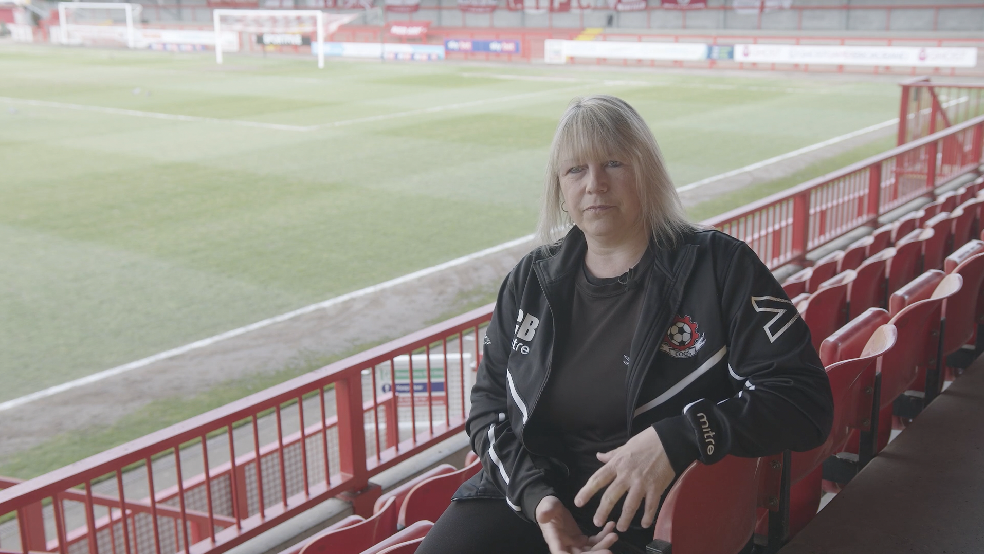 A woman being interviewed at a football pitch