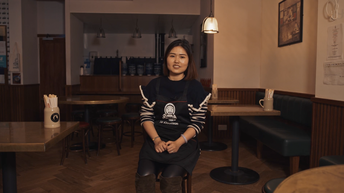 A woman poses in her restaurant