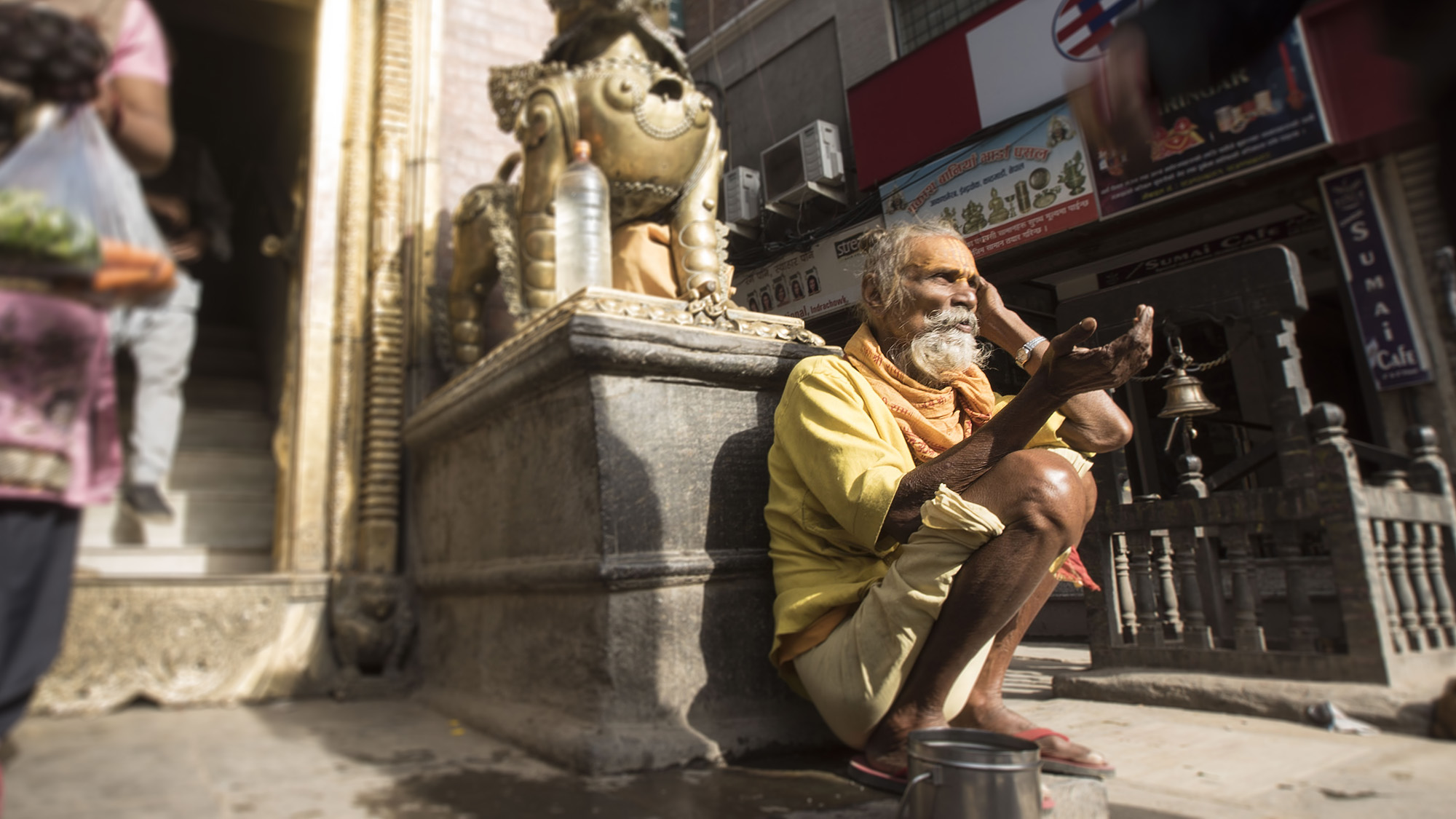 A holy man waits outside a temple for spare change.