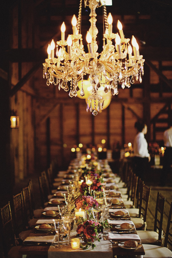 chandelier hanging in vintage restored Dutch barn over long wooden tables