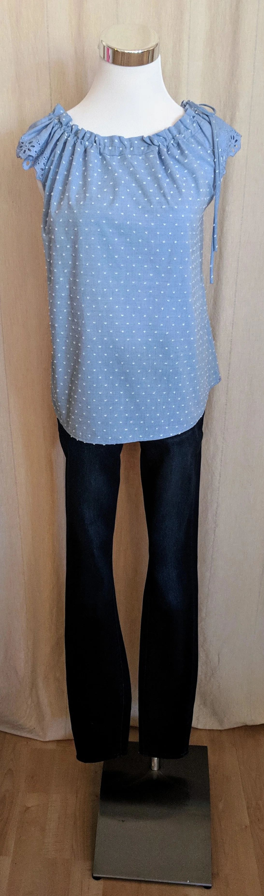 Light blue sleeveless top with tie detail on collar. 