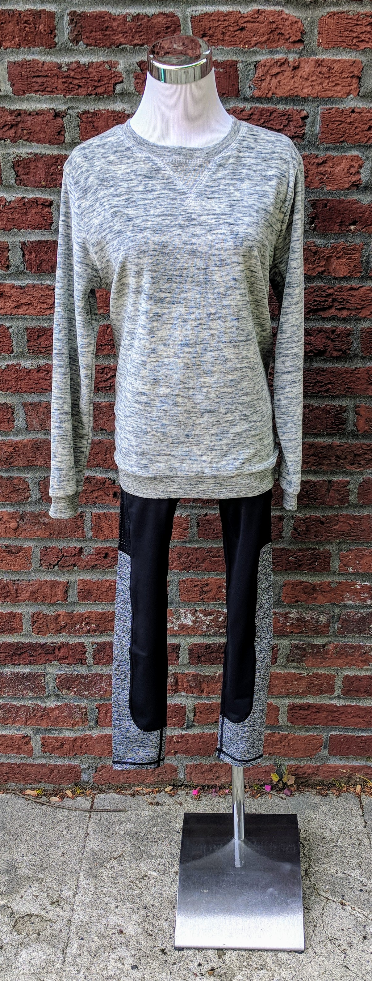 Grey cozy long sleeve sweater paired with black leggings with cut out details on legs. 