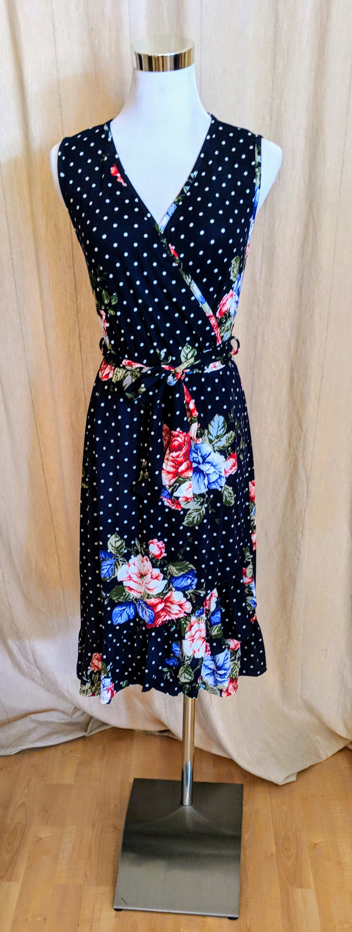 Navy sleeveless polka-dot and floral wrap dress with ruffled hem and tie on waist. 