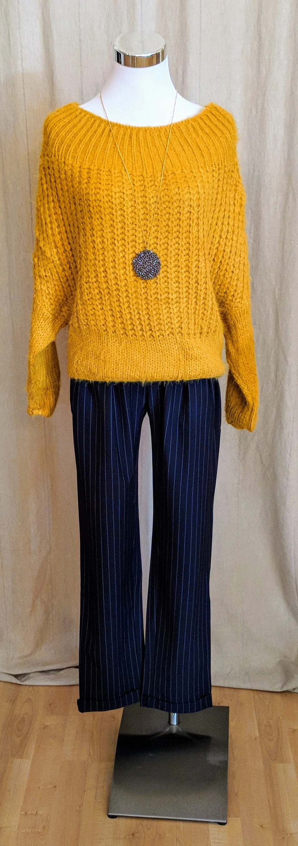 Mustard boat neck long sleeve knit sweater paired with navy high waist pleated trousers. 