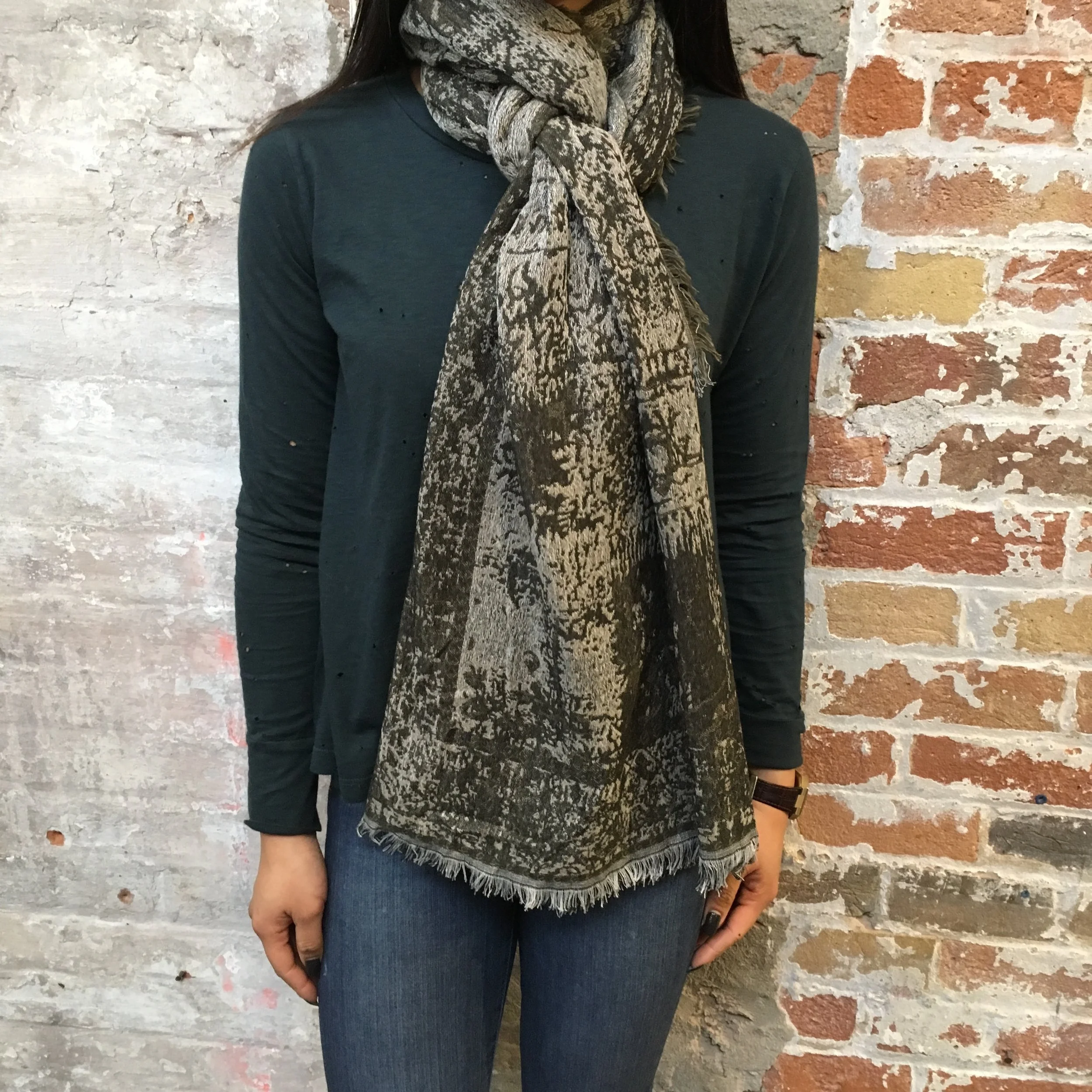 Fold the scarf in half (widthwise) and drape around your shoulders with the loop on one side, and two ends on the other. Take one loose end and pull it through, over and under the scarf loop. Take the second end piece and go under and over the same loop. 