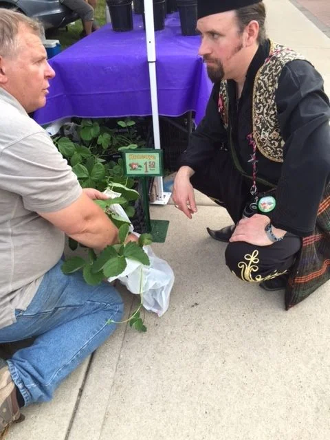 Nox discusses strawberries with a vendor. They're now thriving in his garden!