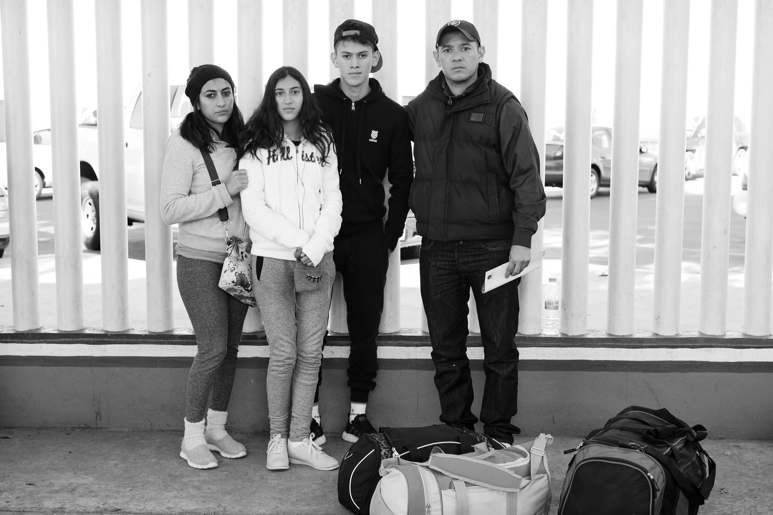 young-migrants-with-luggage-slatted-fence.jpg