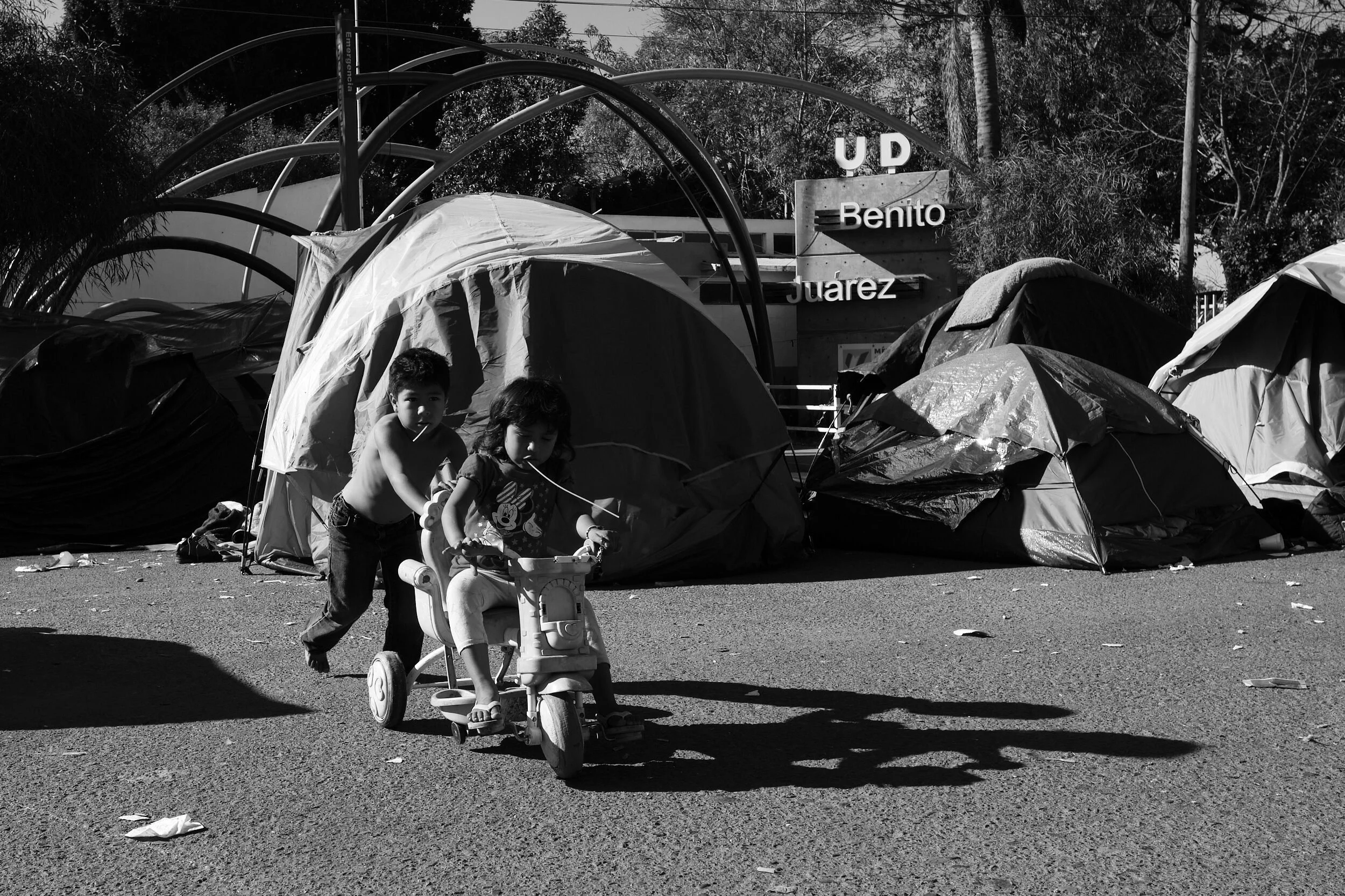migrant-camp-tents-children-riding-toy.jpg