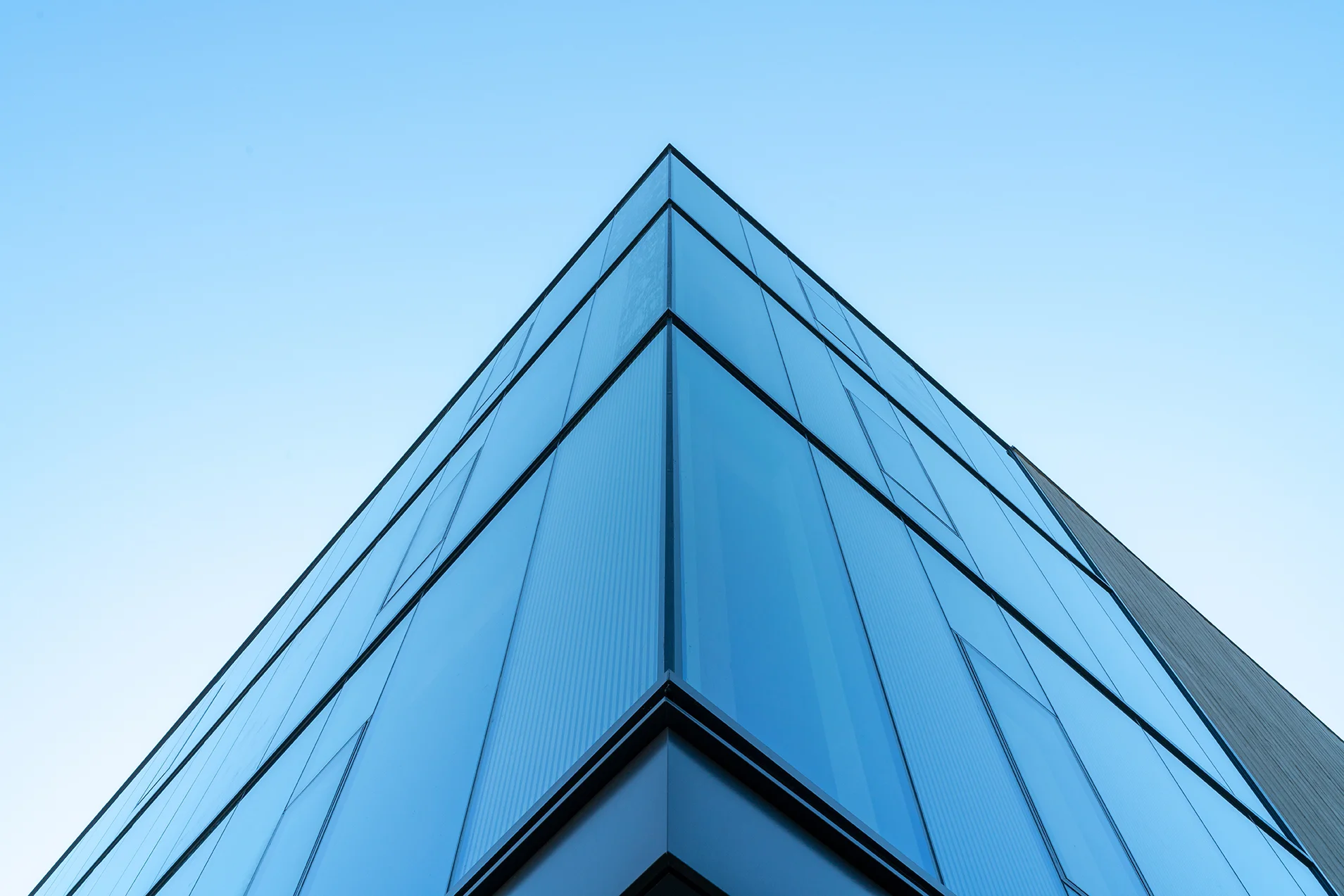 Corner of office building with glass facade from below — William Kaven Architecture