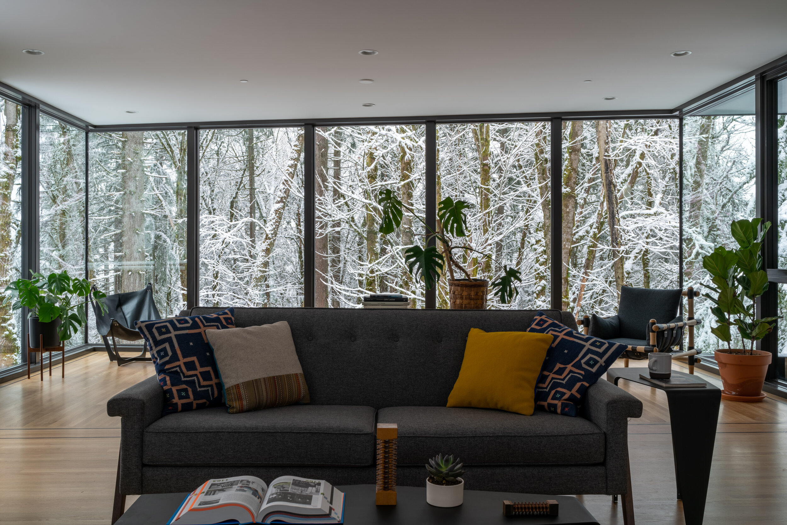 Modern living room with large windows and snowy forest — William Kaven Architecture