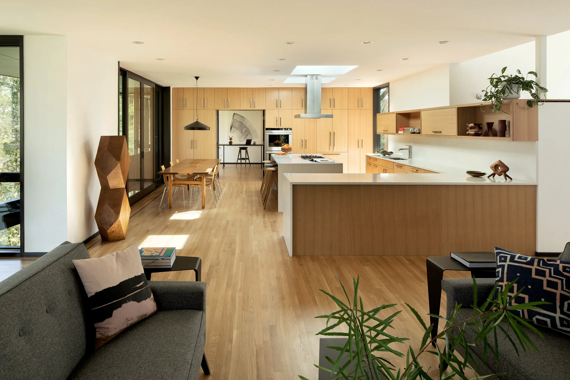 View of modern kitchen from living room, white oak floors — William Kaven Architecture