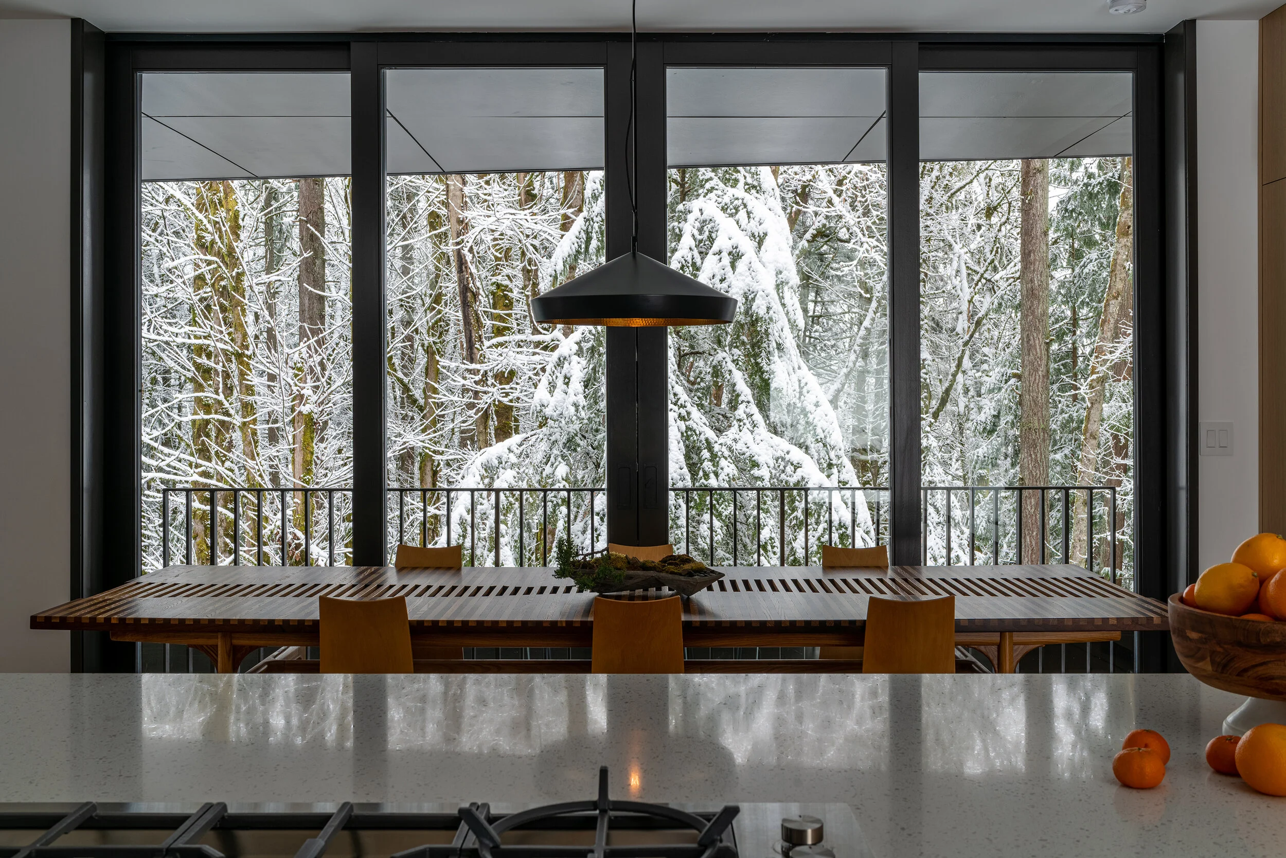 Dining room with snowy forest in background — William Kaven Architecture