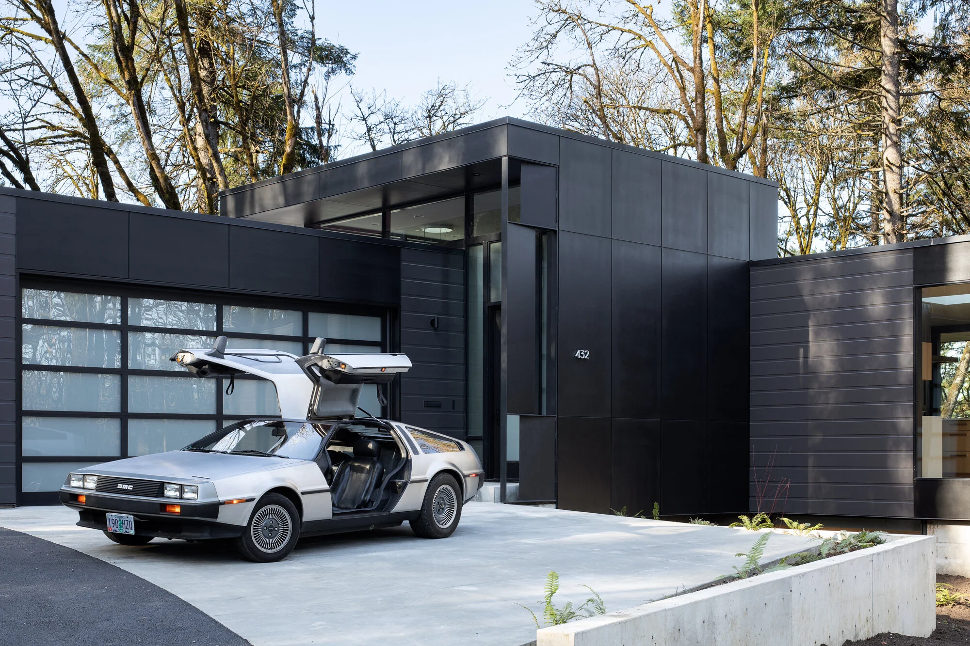 Vintage DeLorean in front of black modern home — William Kaven Architecture