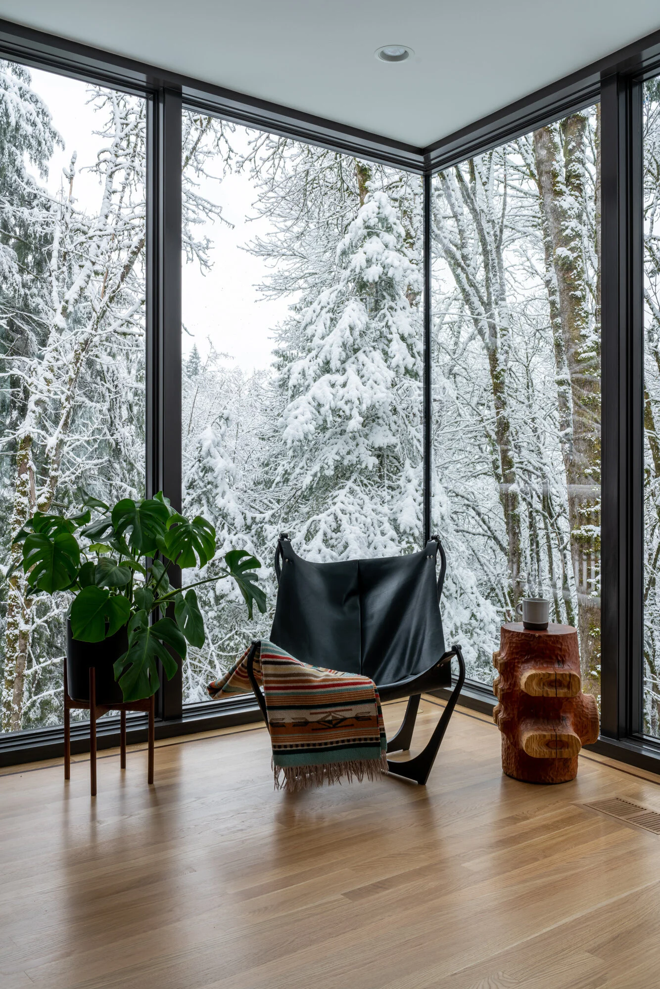 Reading chair in modern living room with snowy forest in background — William Kaven Architecture