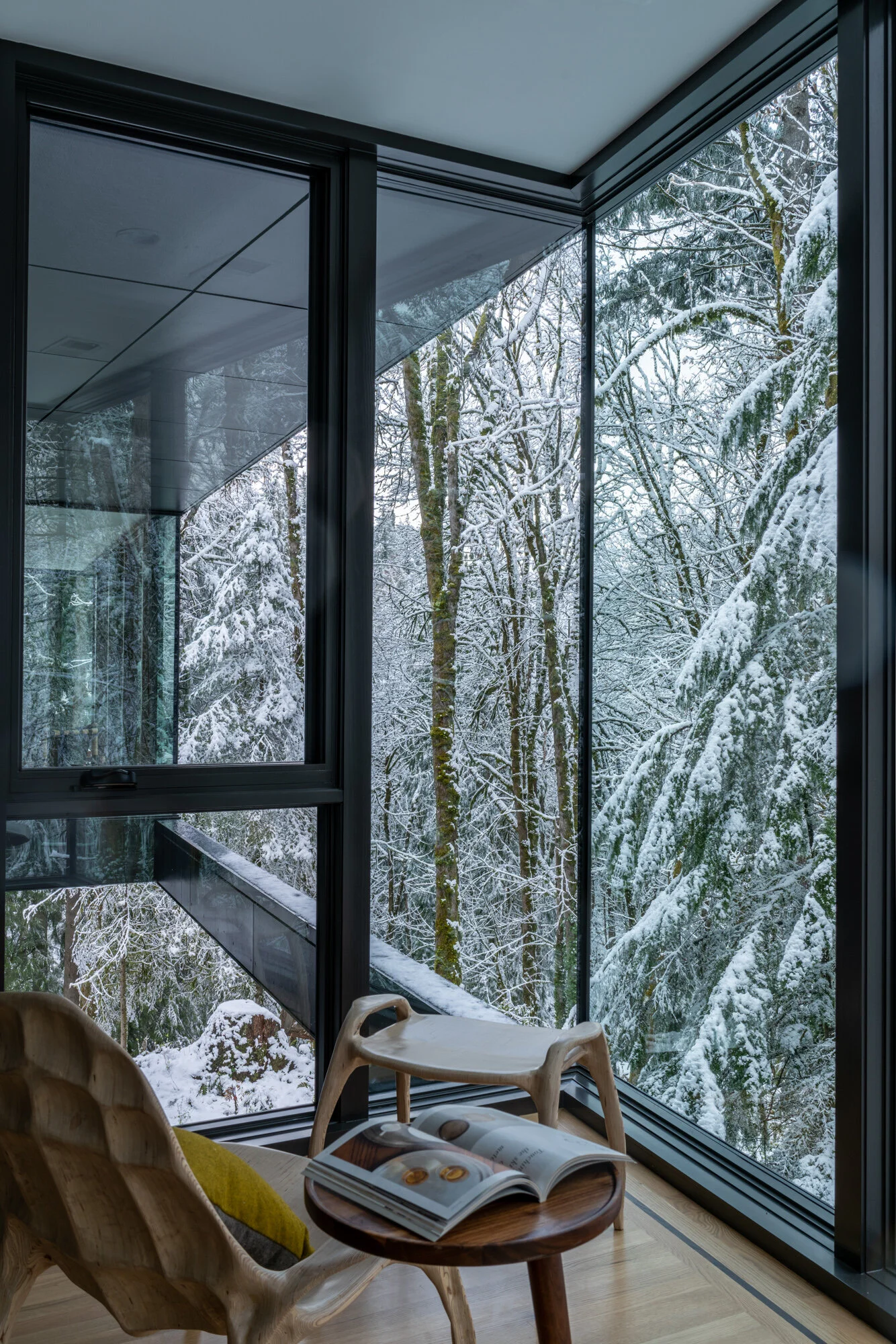 Wooden reading chair with view of snowy forest — William Kaven Architecture