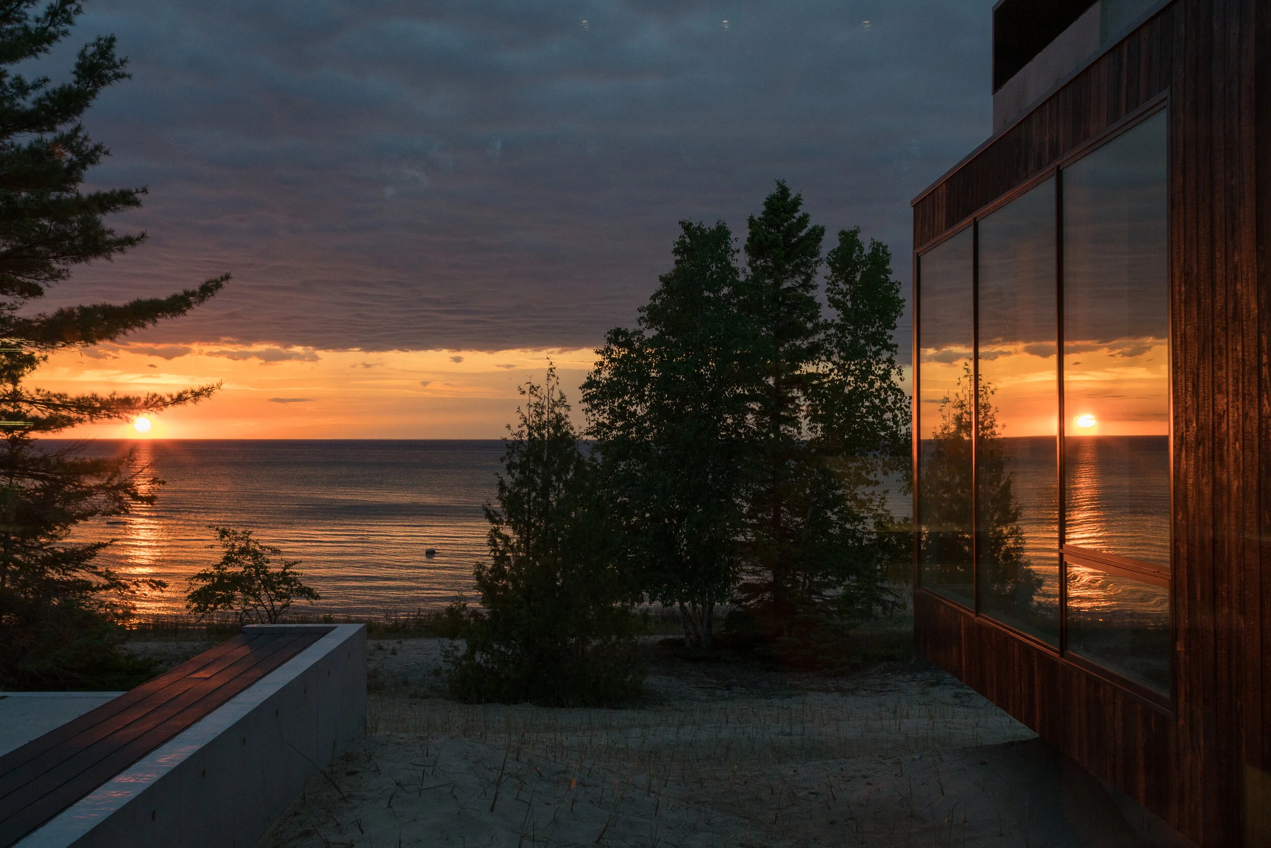 View of Lake Michigan from modern house with sunset in window reflection — William Kaven Architecture