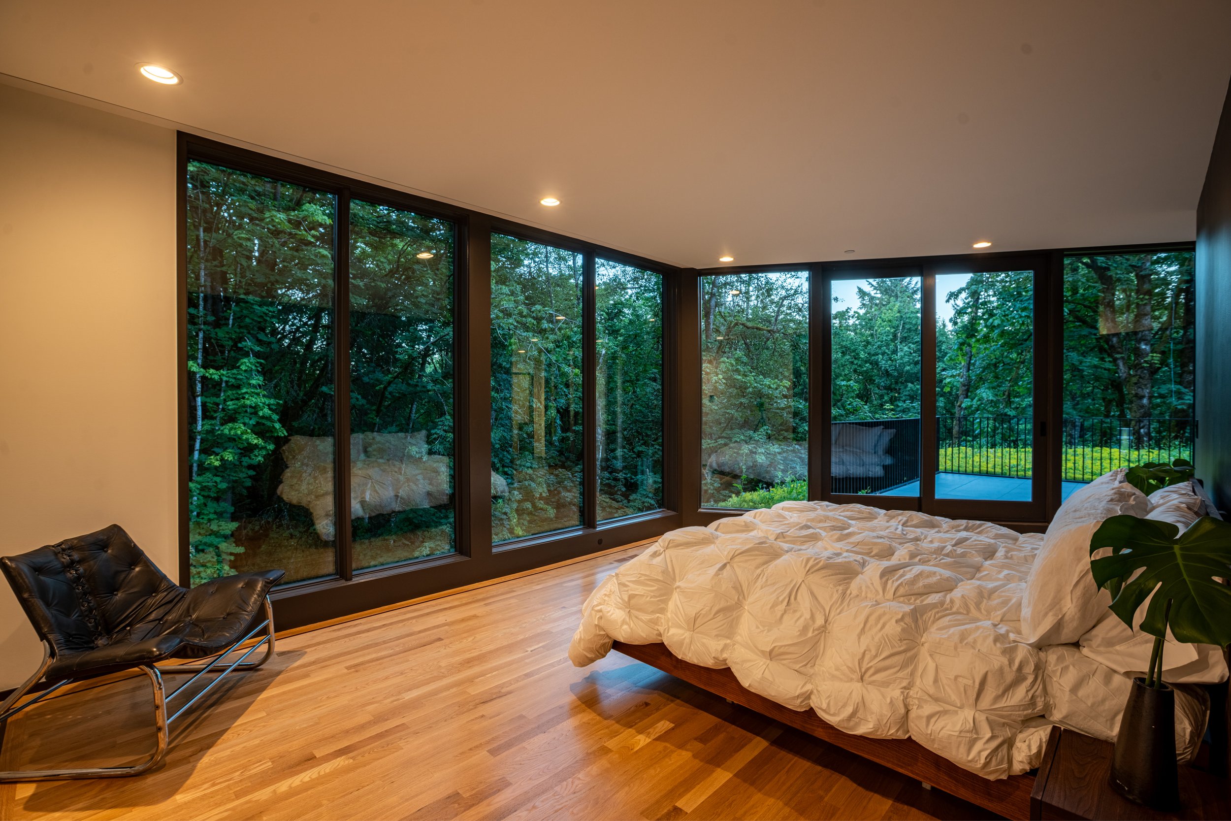 Primary bedroom in modern home with view of forest and terrace with green roof — William Kaven Architecture