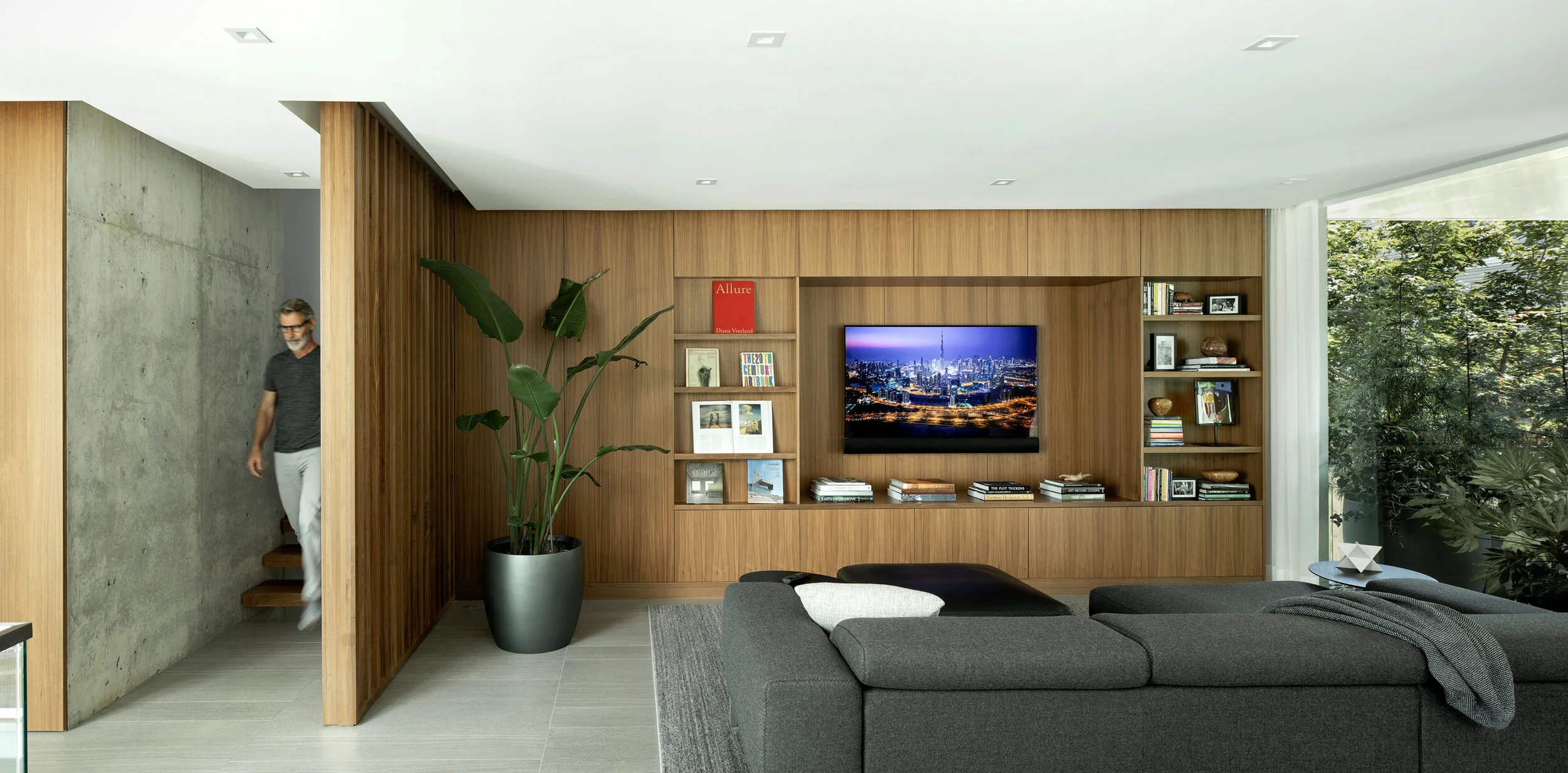 Man entering modern den with walnut casework — William Kaven Architecture