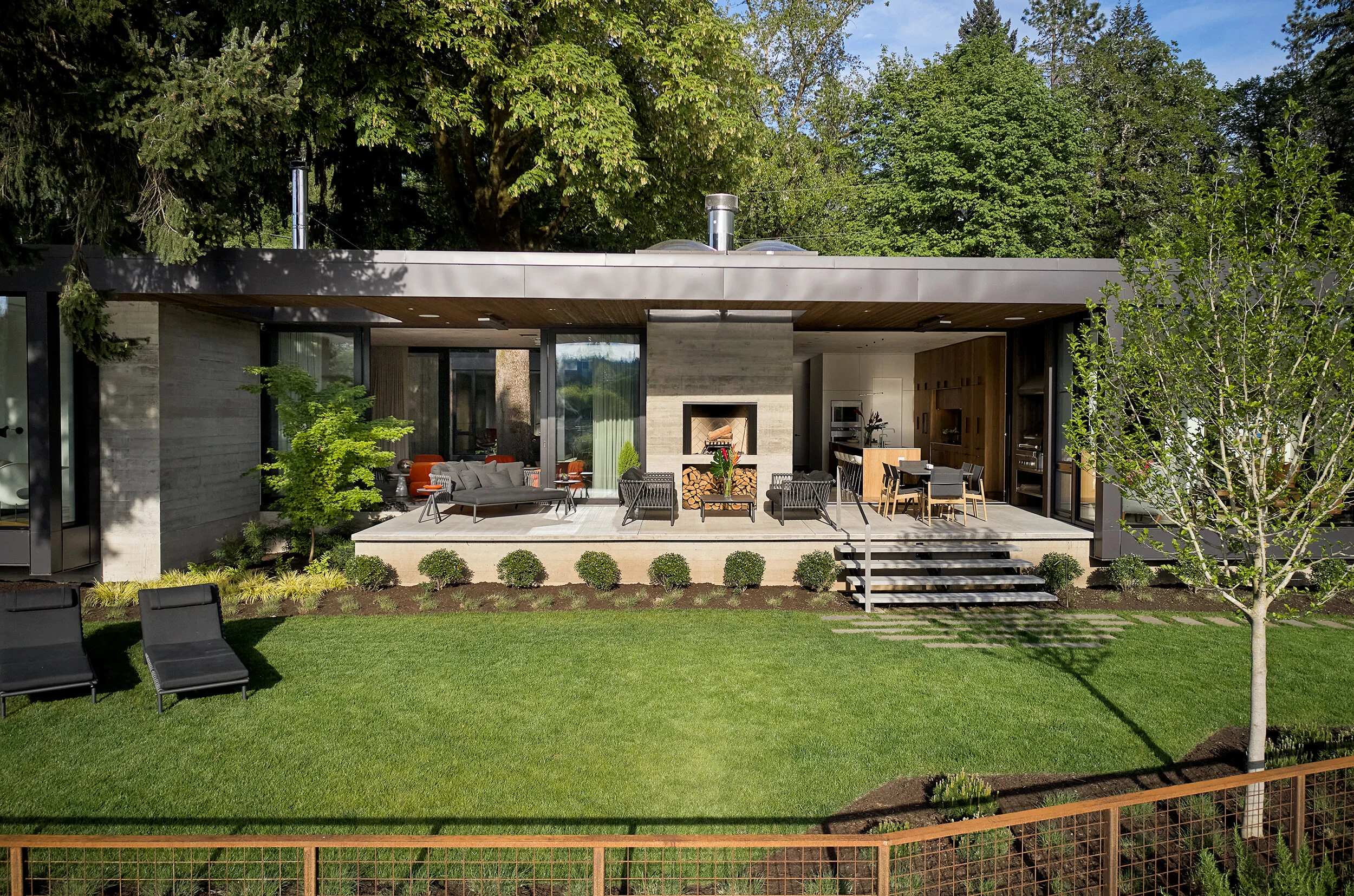 View from river of modern house with terrace and large lawn — William Kaven Architecture