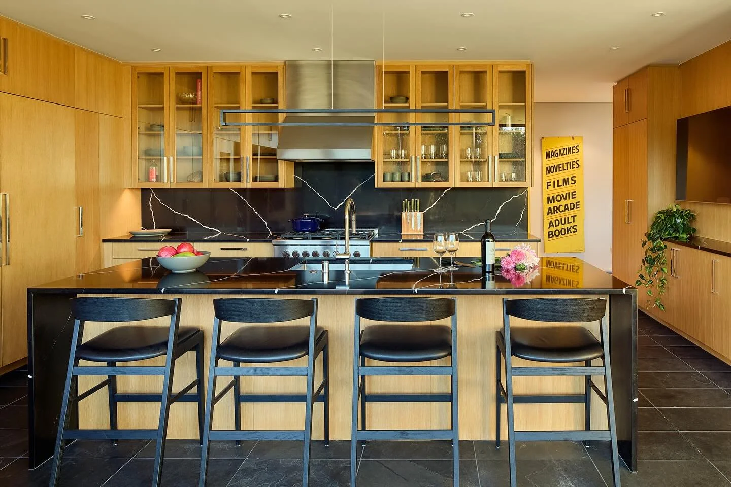 &ldquo;The light-filled kitchen sports white oak cabinetry, state-of-the-art appliances, and an eat-in kitchen island with black granite counters that waterfall off the ends. Behind the range, the white zigzagging veining on the black granite playful