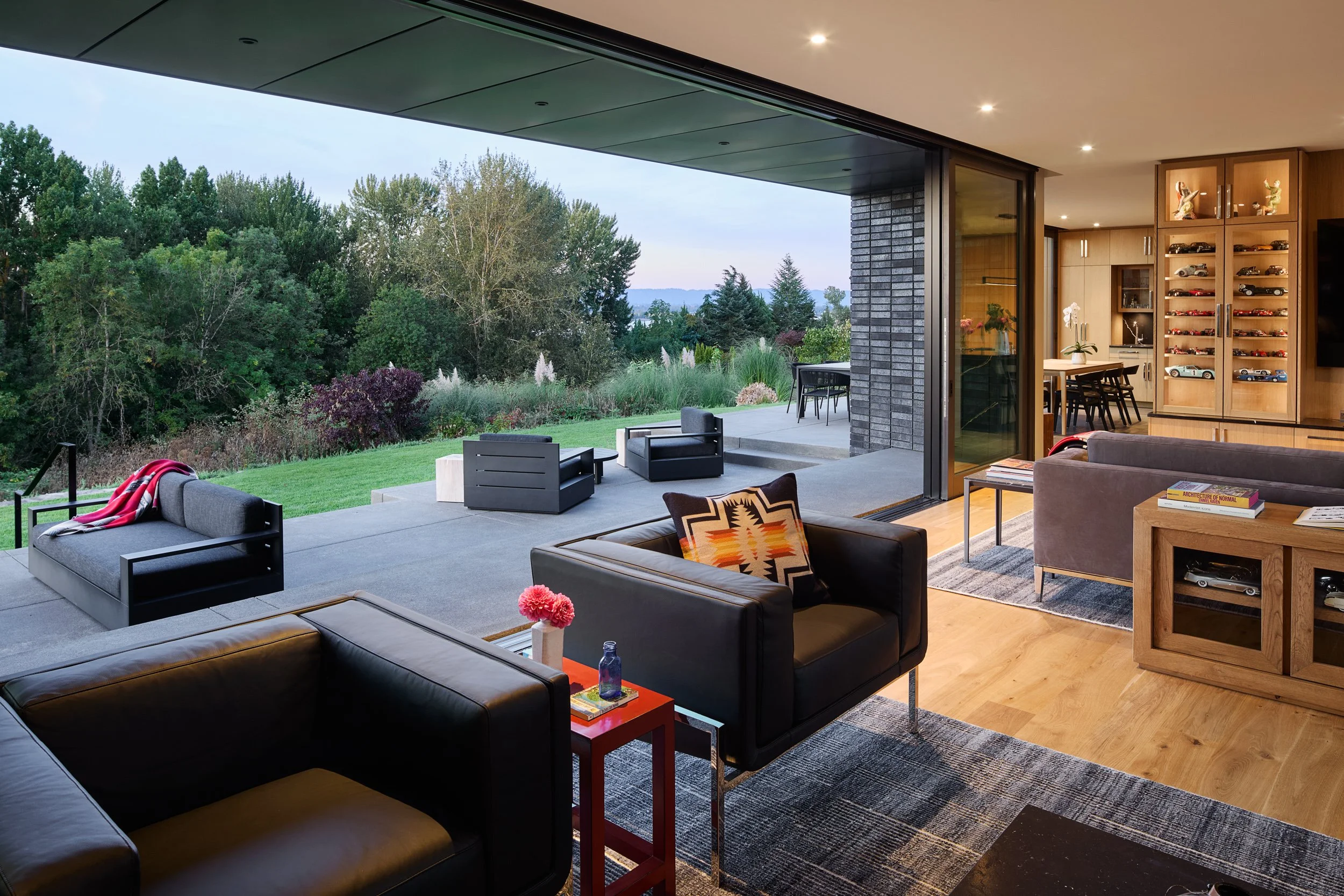 Modern living room with model car display shelves, open to terrace — William Kaven Architecture.