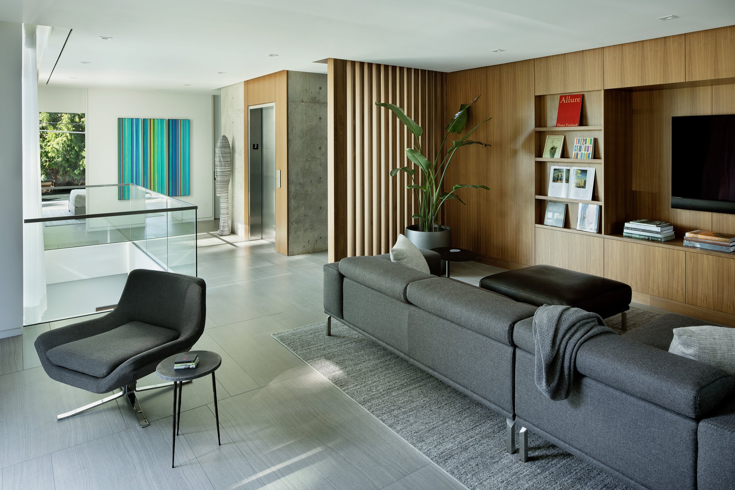 Modern den with walnut casework, slatted walls, and elevator — William Kaven Architecture