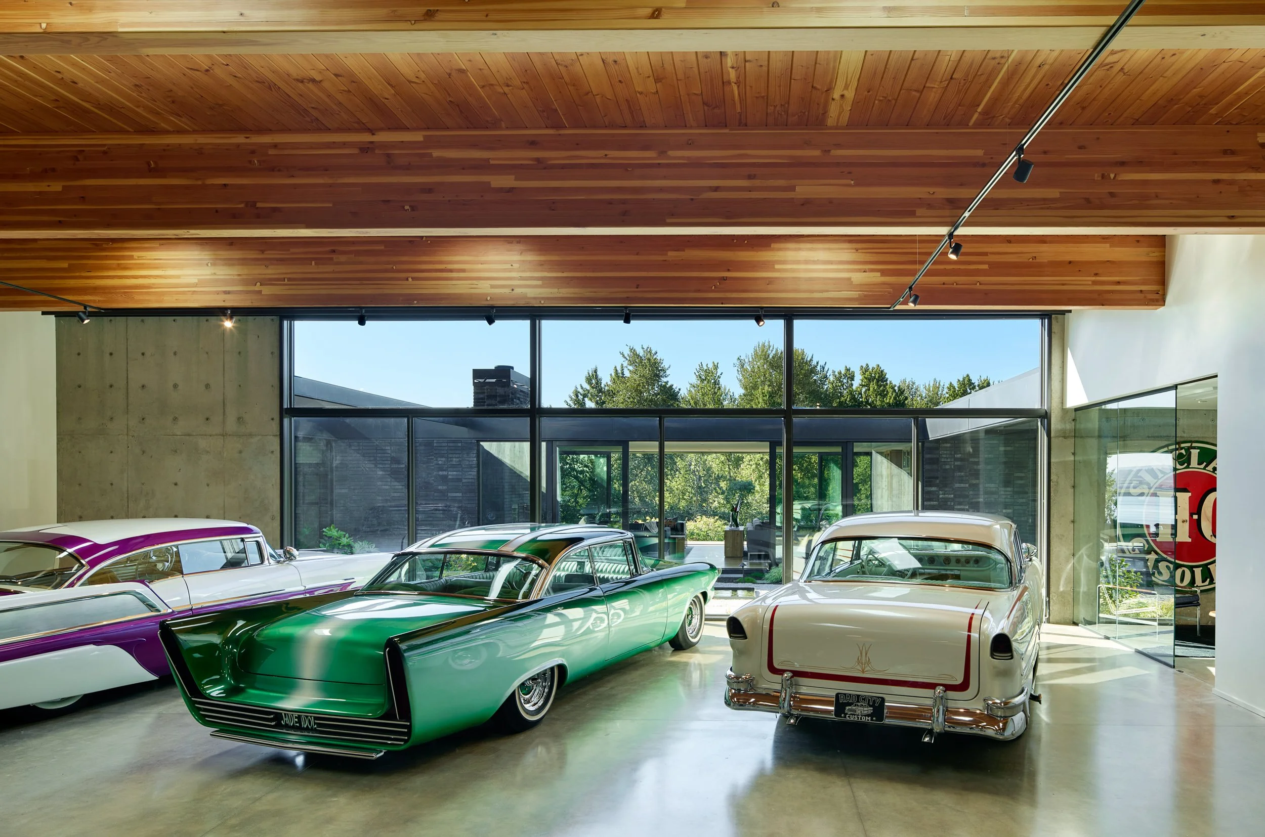 Car gallery with custom classic cars and view of courtyard — El Capitola residence by William Kaven Architecture