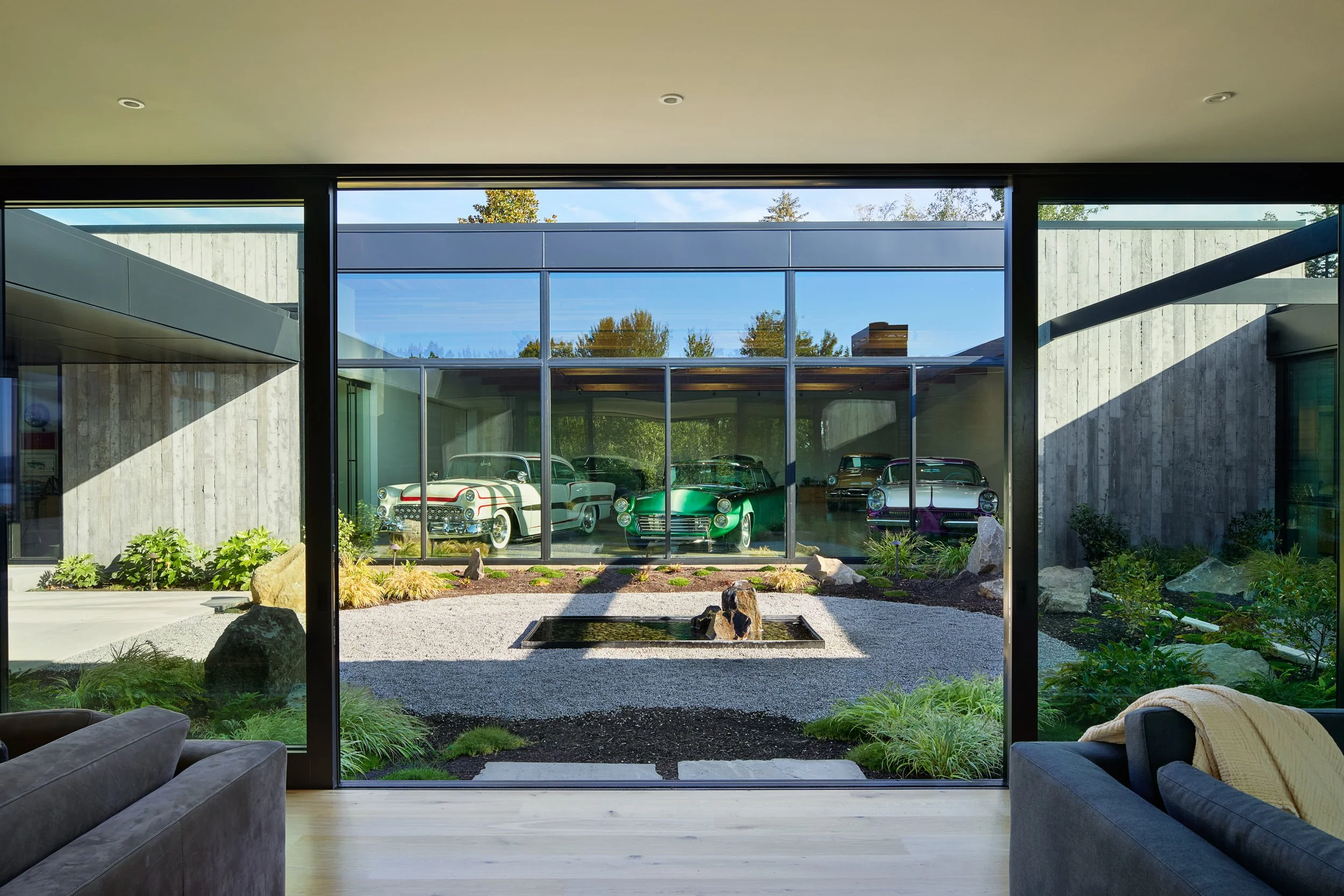 View across courtyard into gallery with custom classic cars — El Capitola residence by William Kaven Architecture