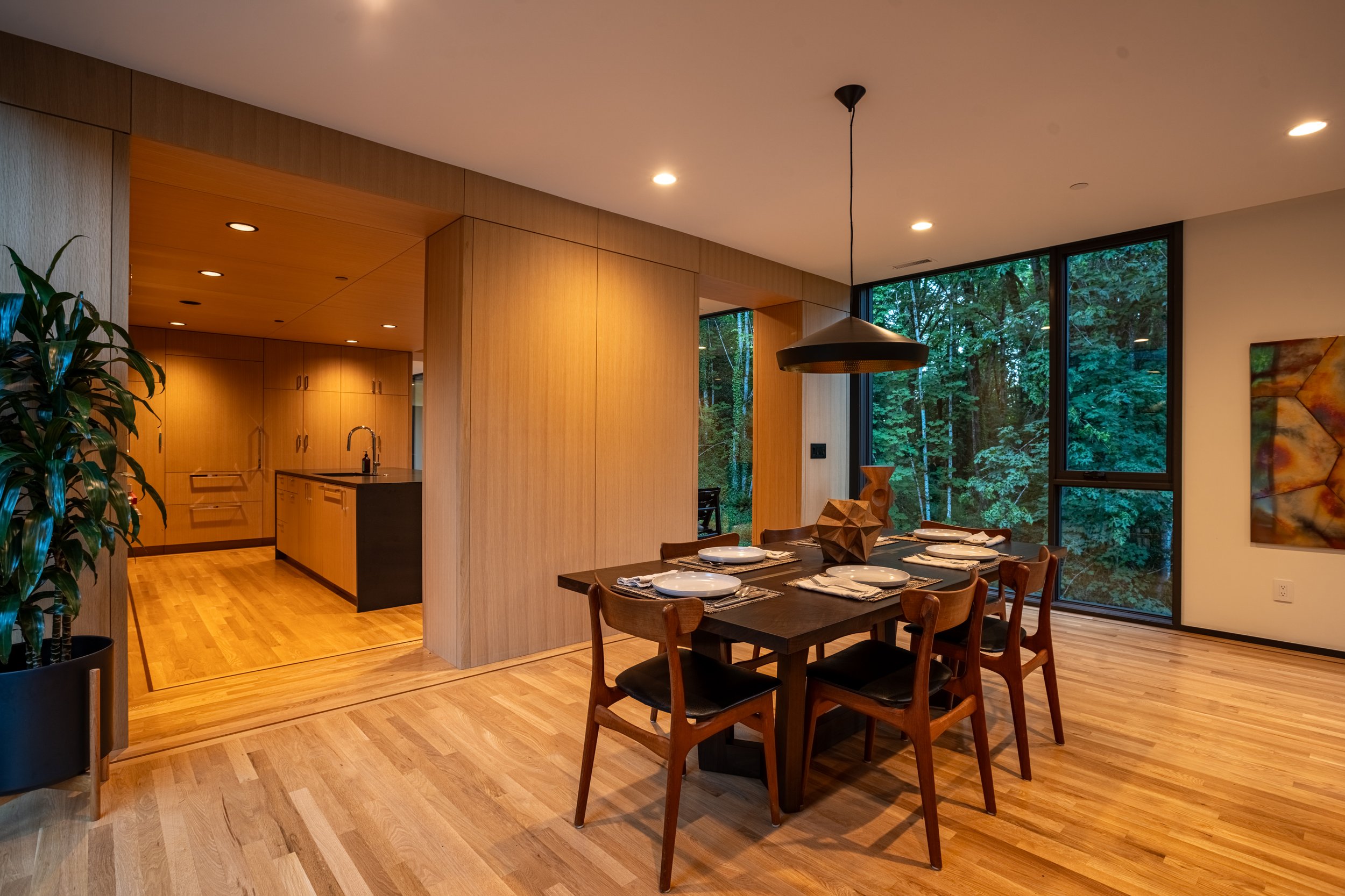 Dining room with Tom Dixon pendant lamp and view of forest — William Kaven Architecture