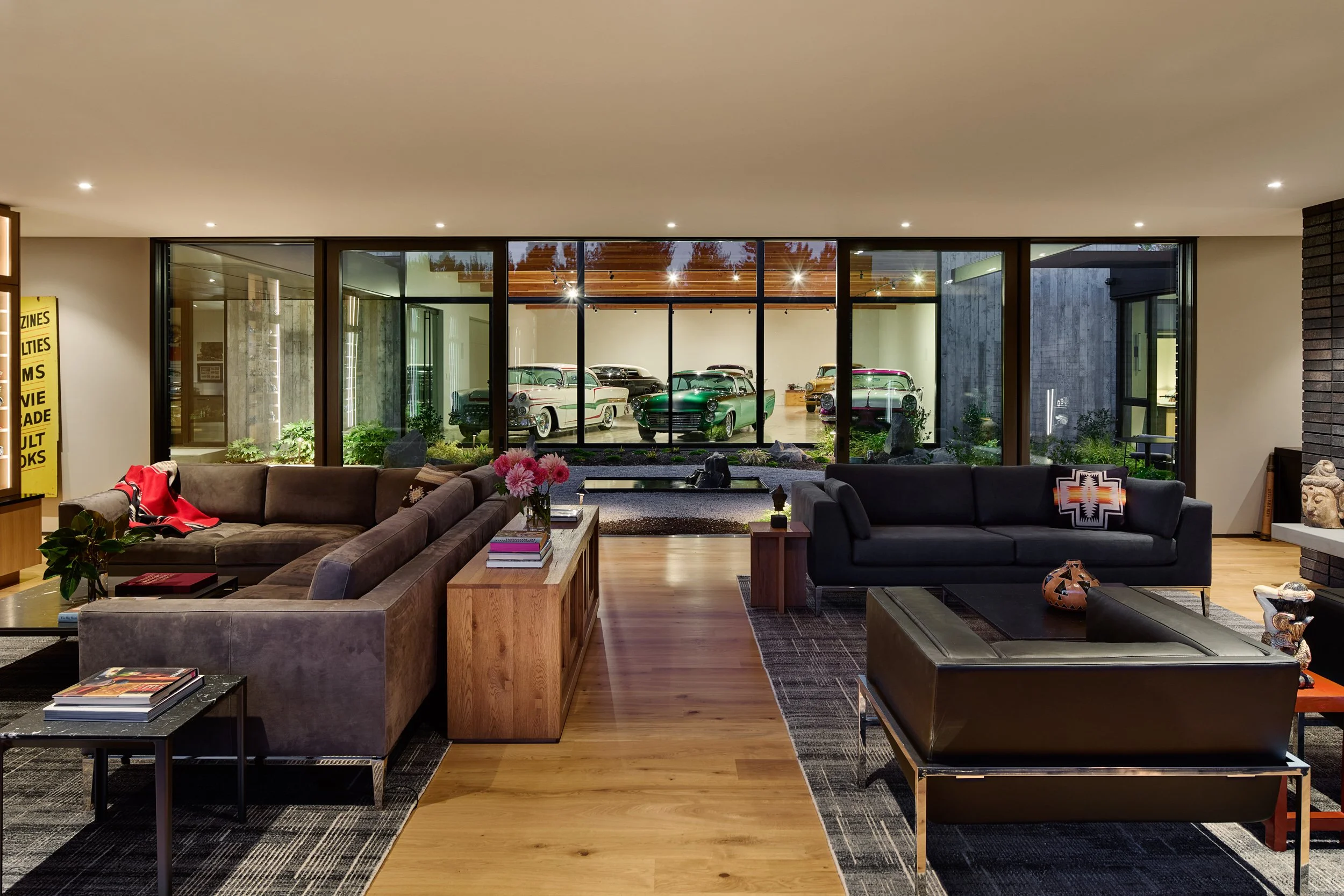 Modern living room with view into car gallery with custom classic cars — William Kaven Architecture.
