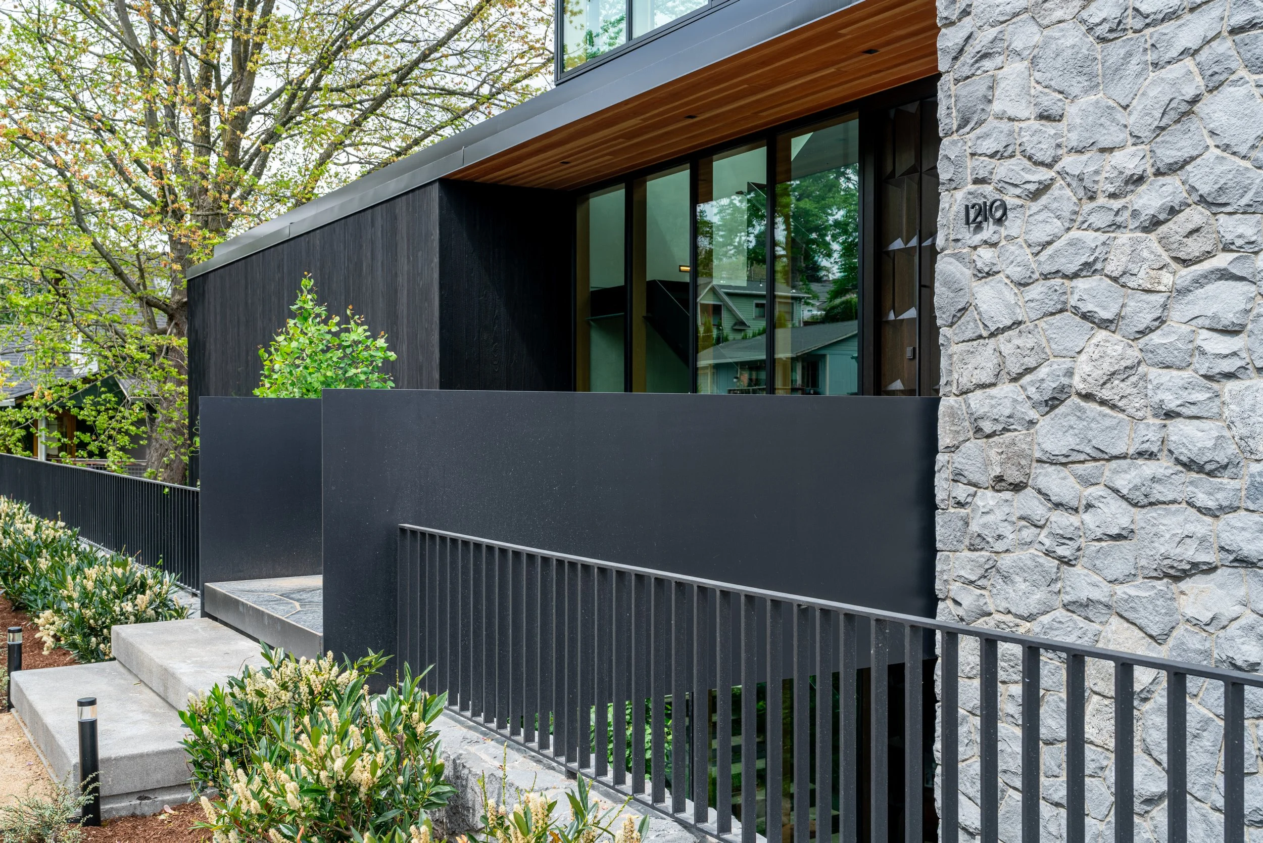 Entry to modern house with black steel, shou sugi ban, and stone cladding — William Kaven Architecture
