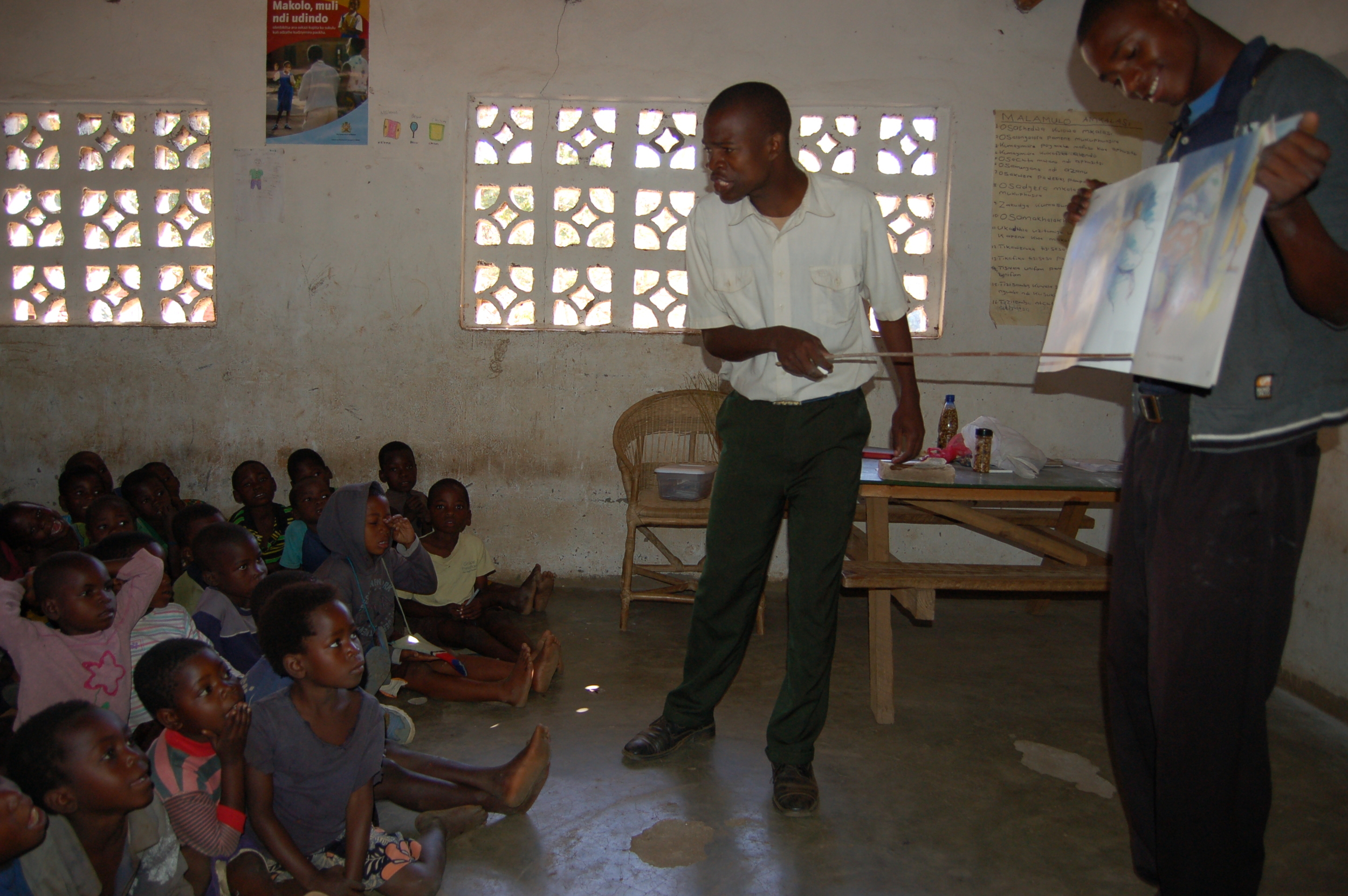 Simeon (holding book) teaching with another Grace Center staff member. 
